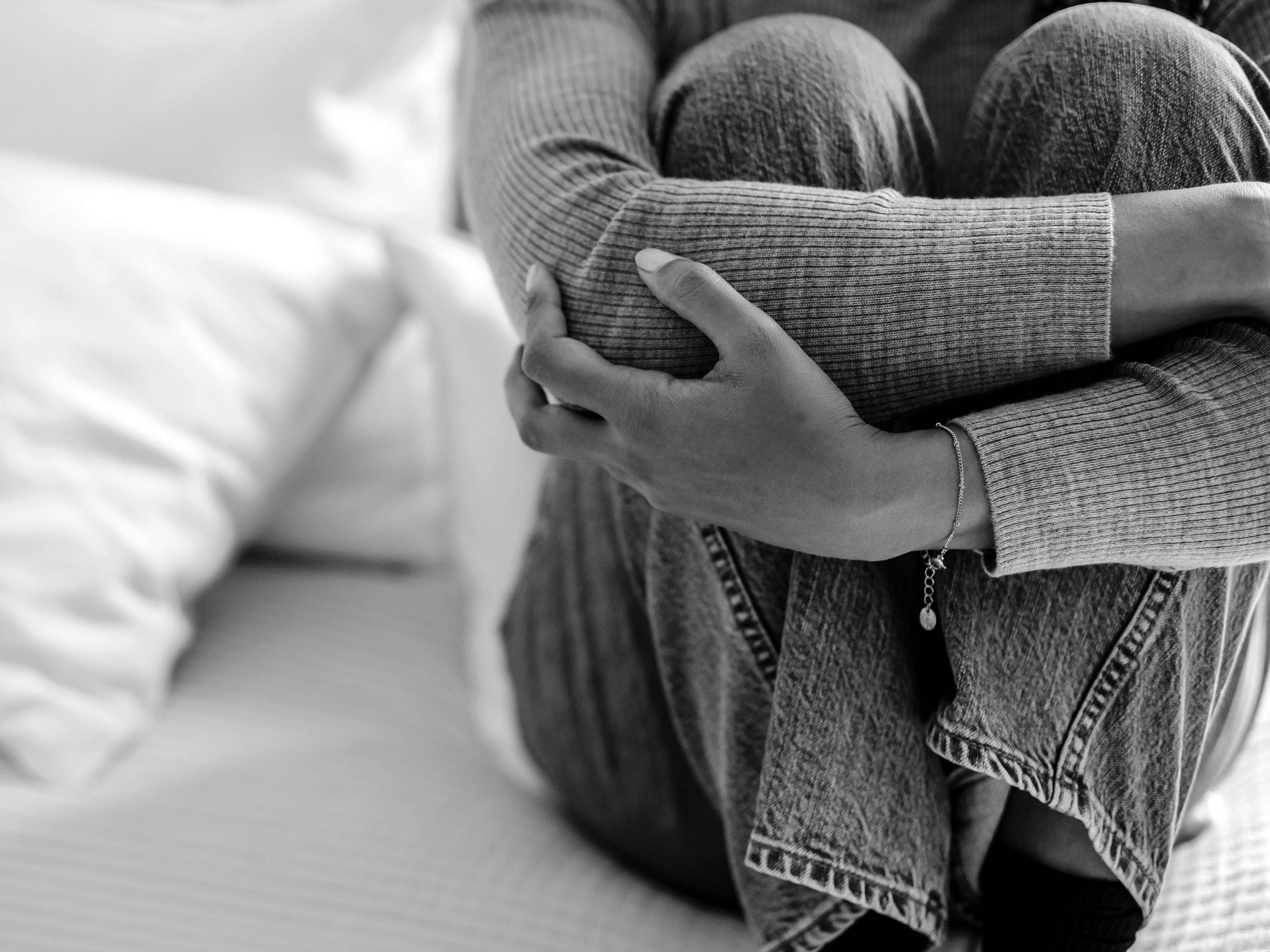 A woman crouching on a bed | Source: Pexels