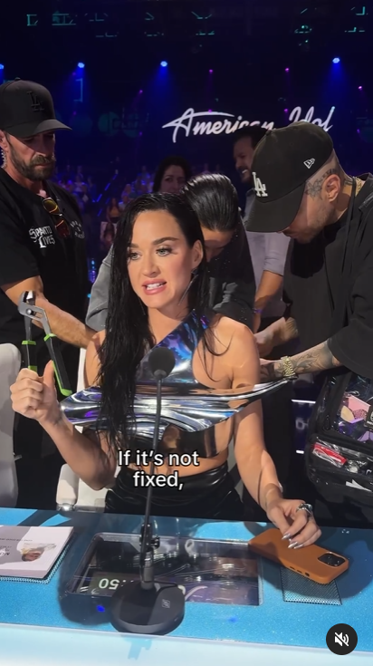 A screenshot of Katy Perry holding a pair of pliers as staff members fix her outfit during the live broadcast of "American Idol." | Source: Instagram/katyperry