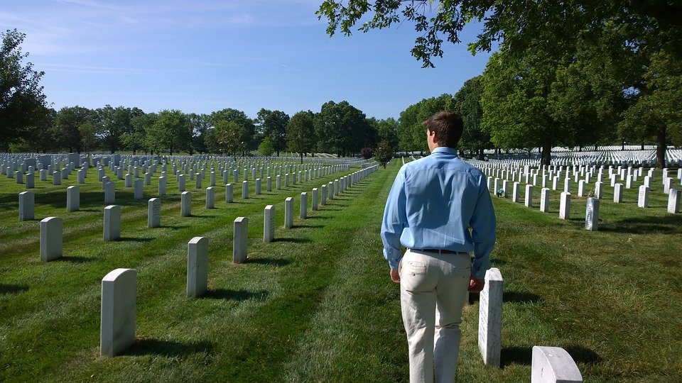 A man visiting a dead loved one at the cemetery. | Photo: Pixabay