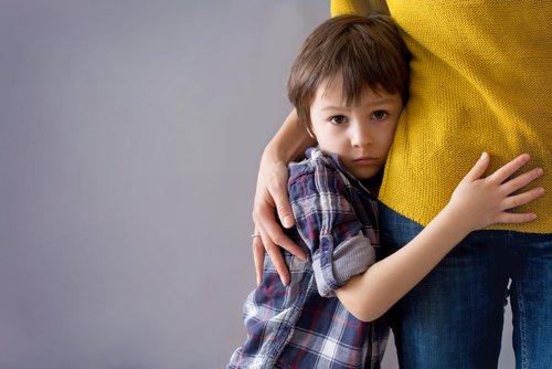 Junge versteckt sich am Bein seiner Mutter | Quelle: Shutterstock