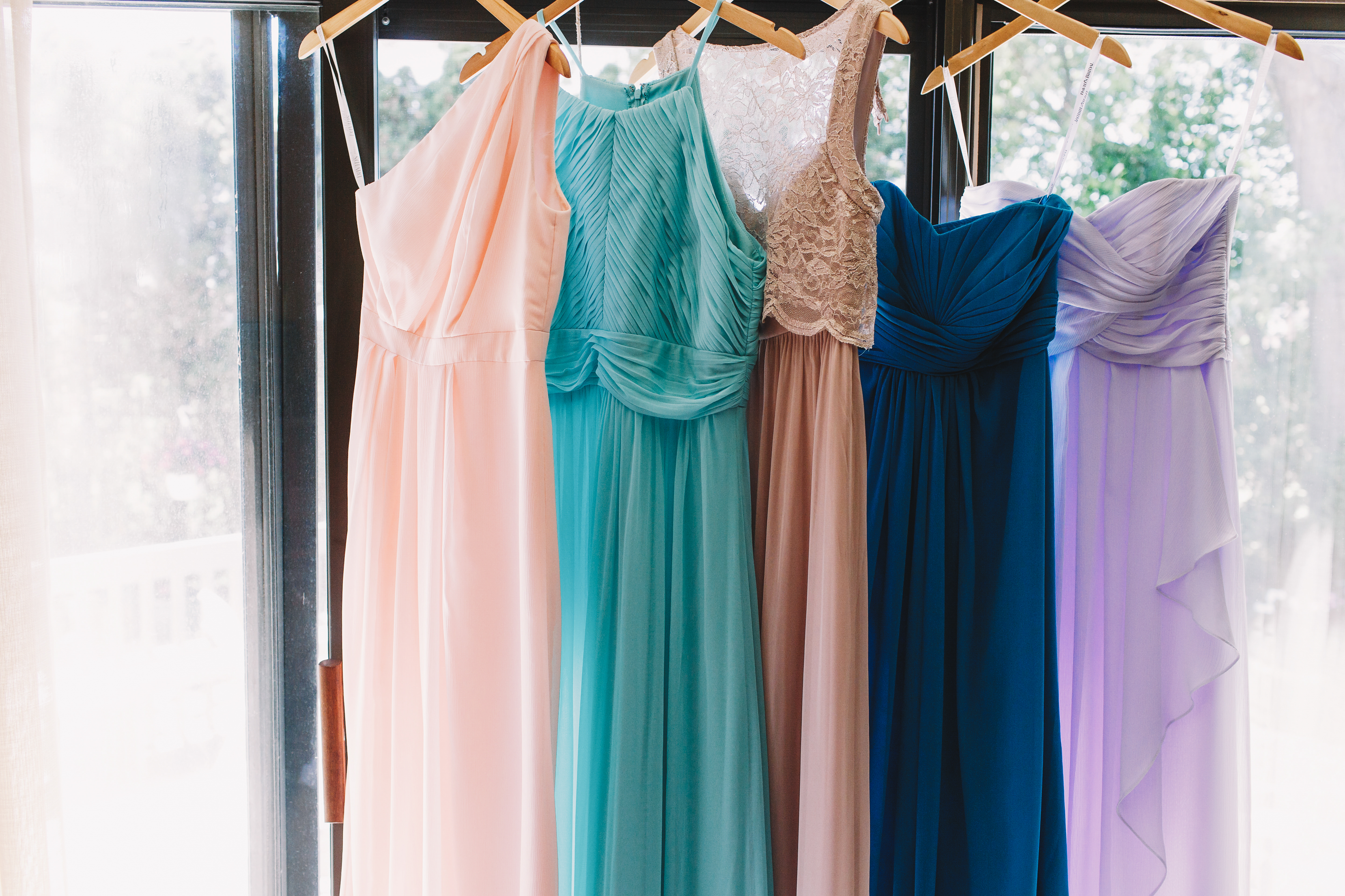 Several bridesmaid dresses hanging from a rod | Source: Shutterstock