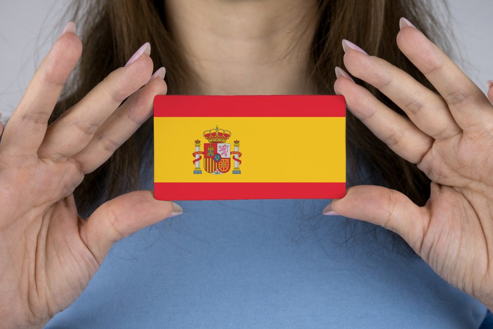 Mujer sosteniendo una tarjeta con la bandera de España plasmada sobre ella. | Foto: Shutterstock