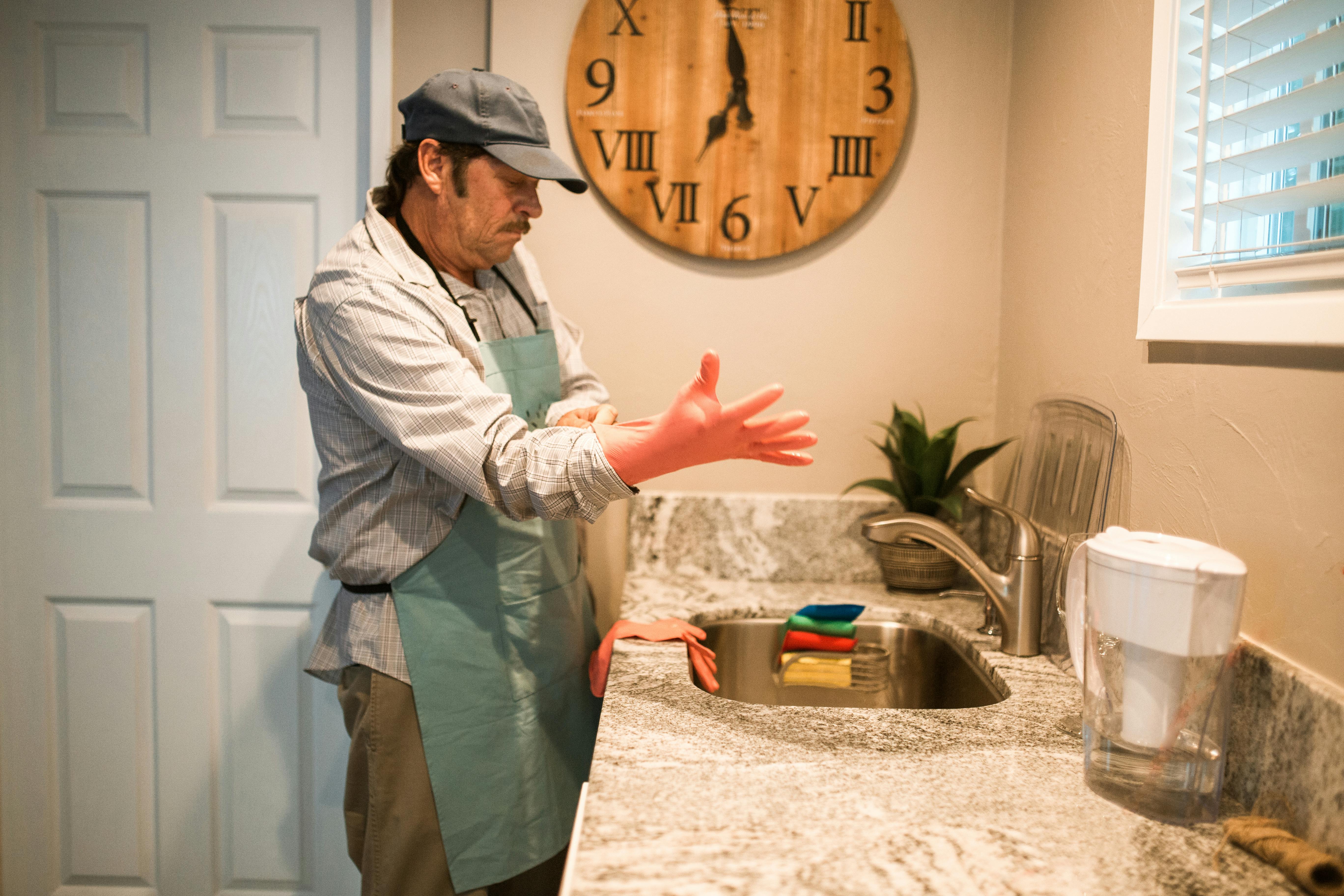 A man wearing gloves while standing in front of a sink | Source: Pexels