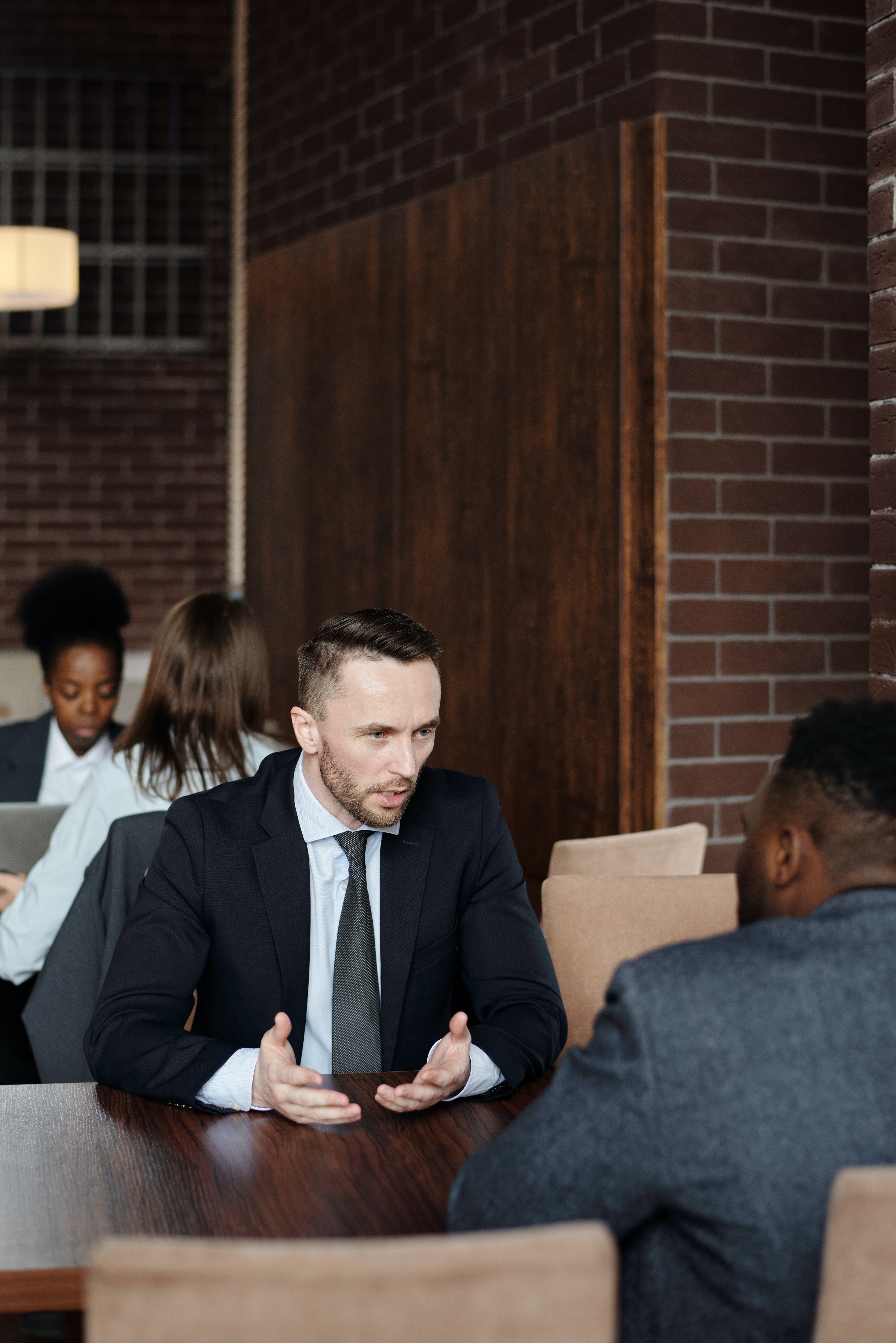 Two men in suits having a conversation. | Pexels/ August de Richelieu