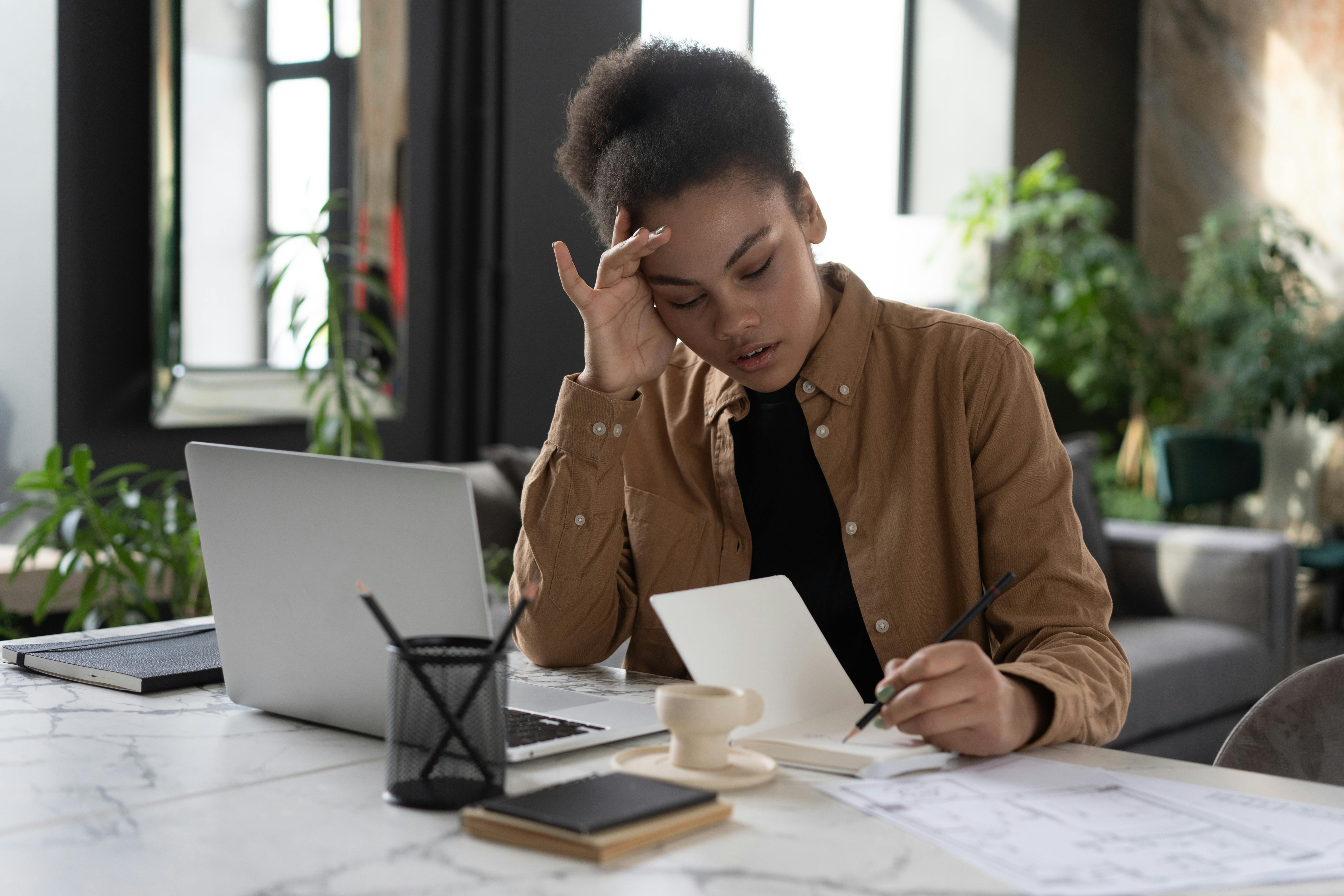 An unhappy and frustrated woman looking at something in a notebook | Source: Pexels