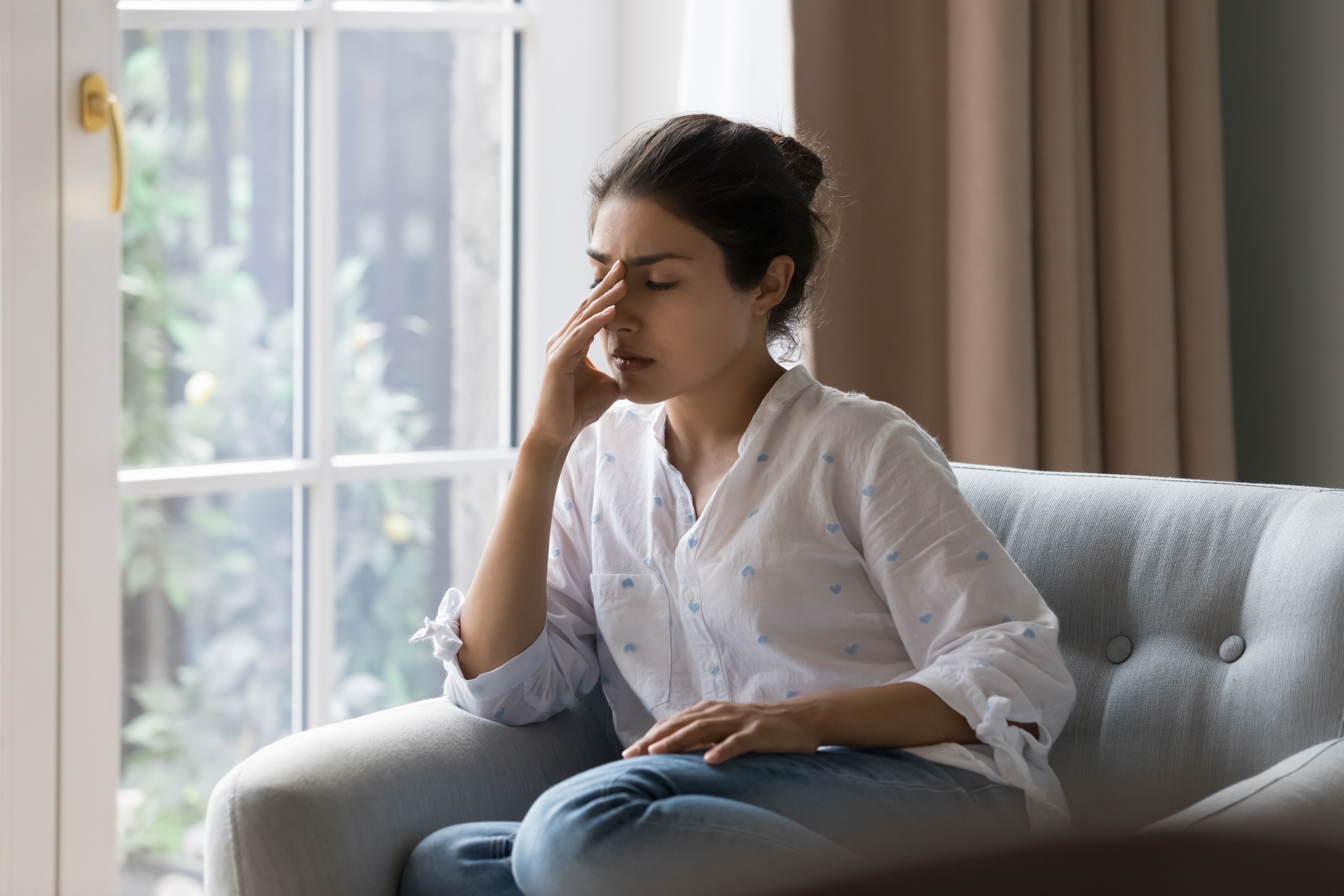 A frustrated woman sitting on a sofa | Source: Shutterstock