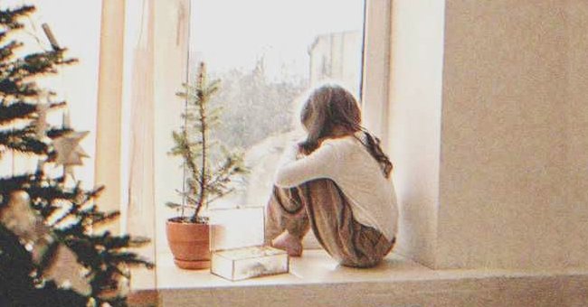 A sad girl looking out a window | Source: Shutterstock