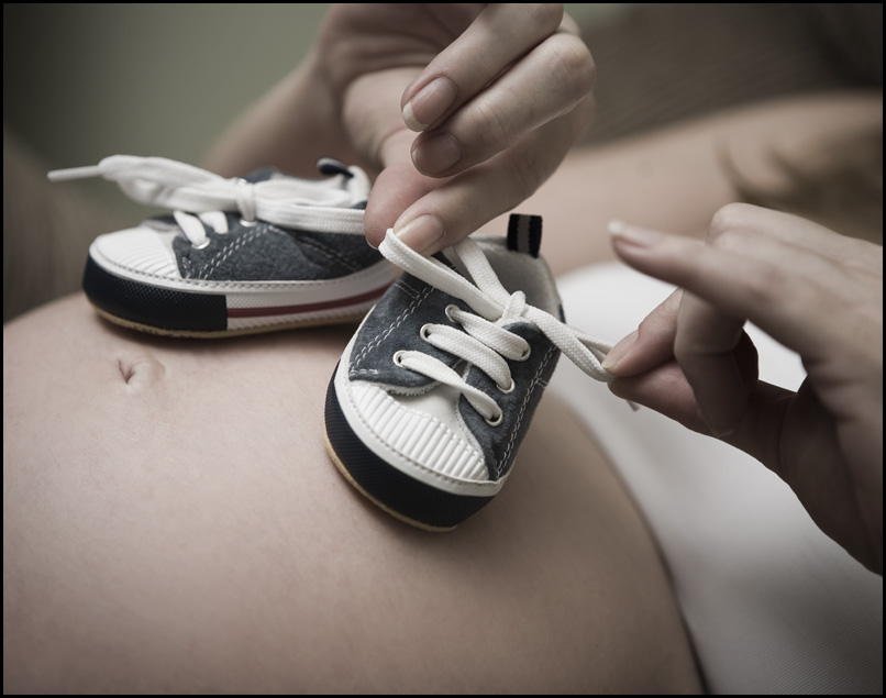 Baby shoes placed on a pregnant woman's belly | Source: Flickr