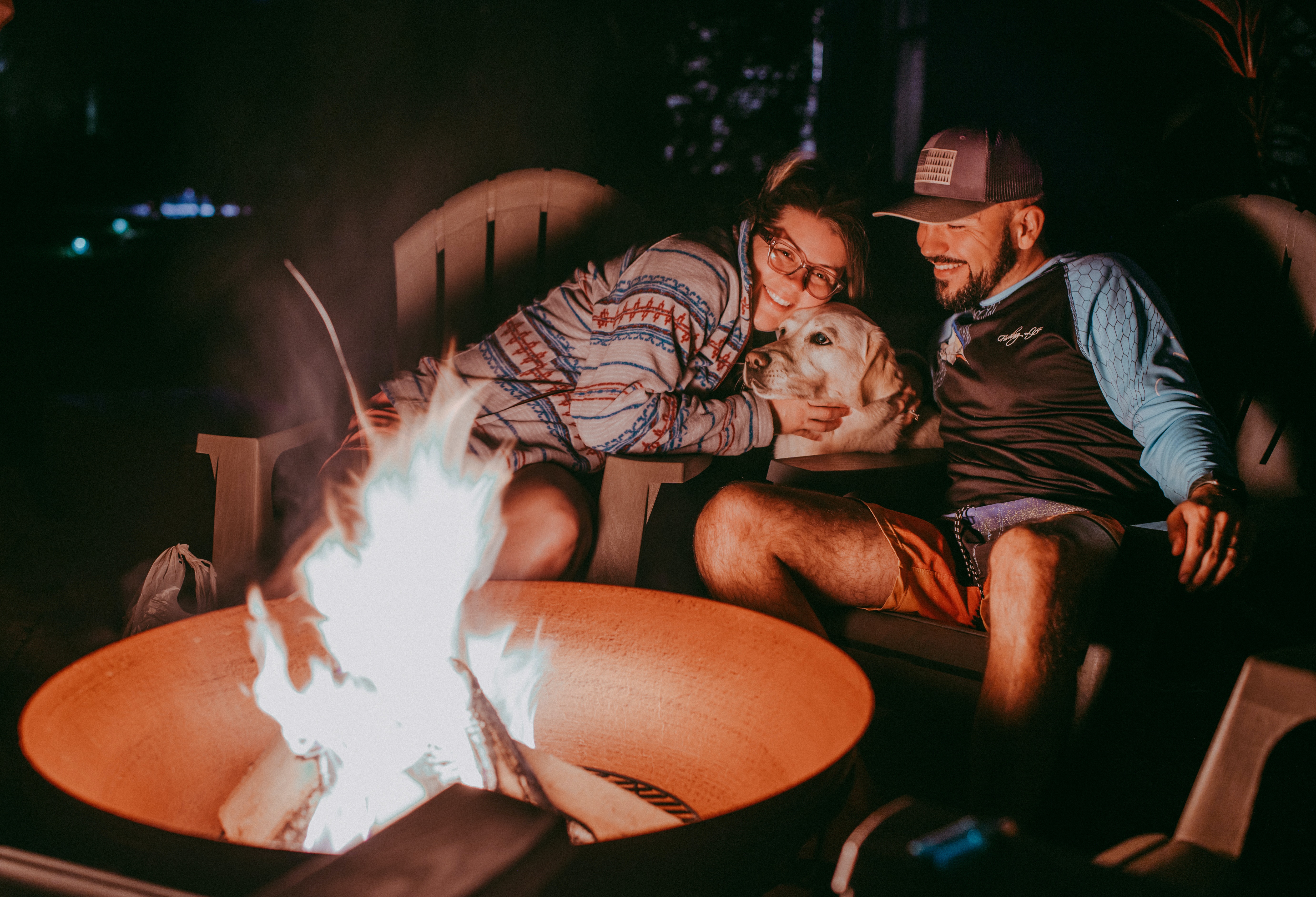 Two people sitting in front of a fire with their dog. | Source: Pexels