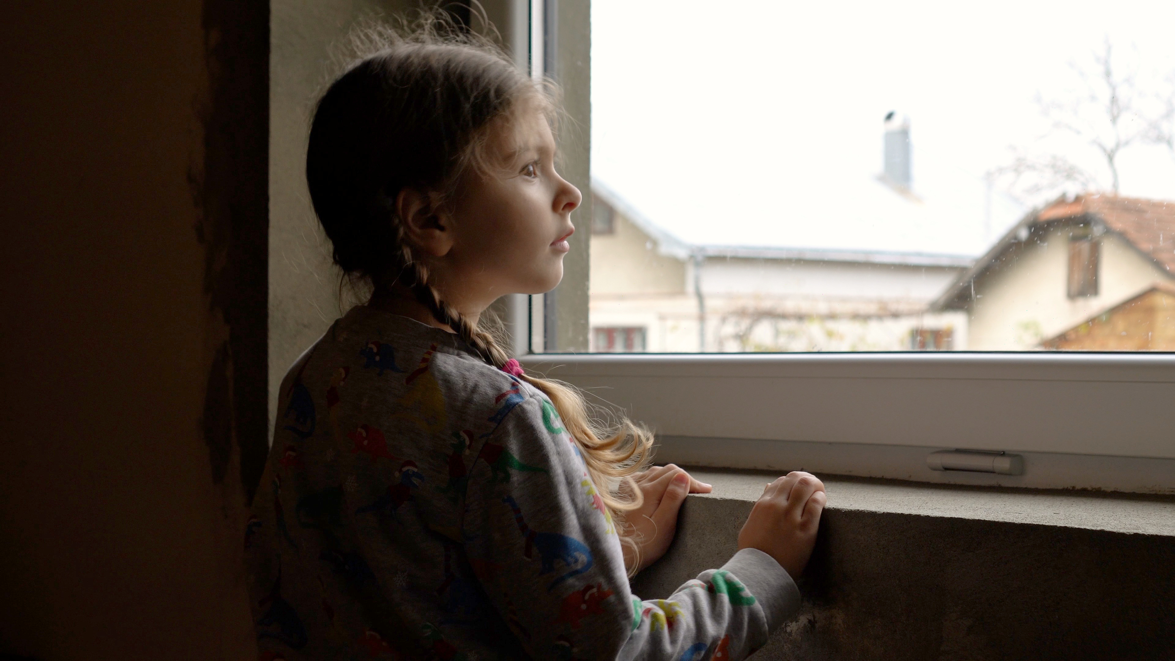 Girl looks through the window | Source: Shutterstock.com