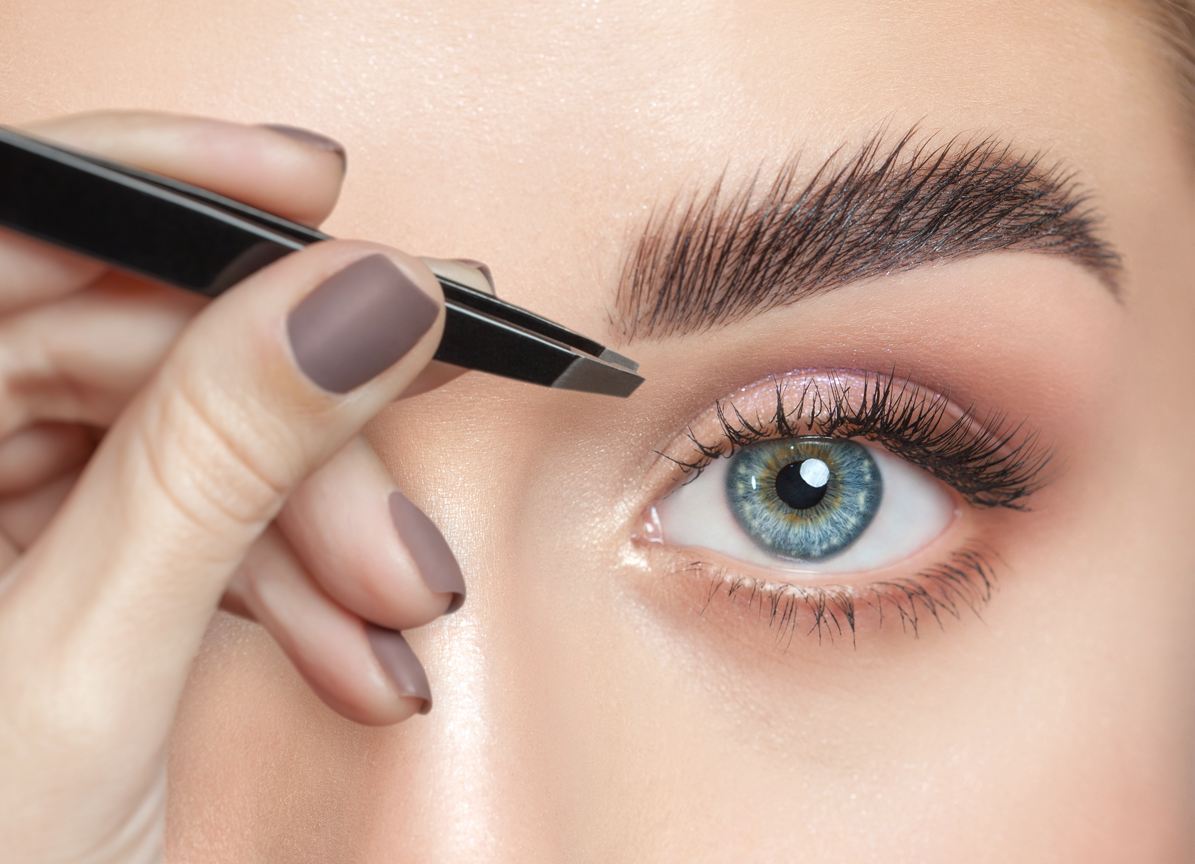 Woman plucking eyebrows | Source: Shutterstock