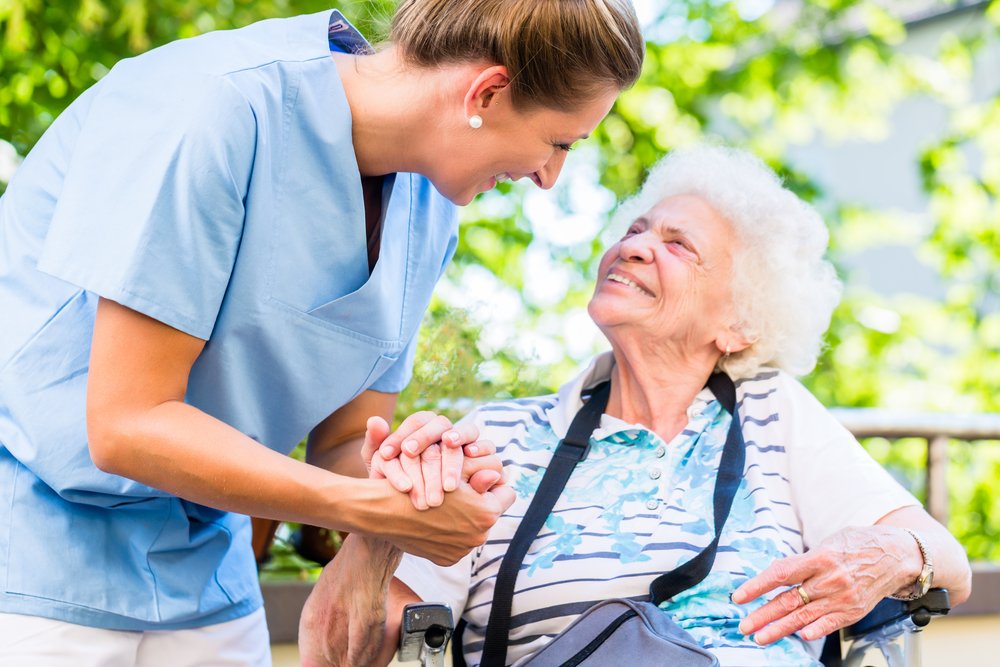 Enfermera toma de la mano a una mujer mayor en una pensión. | Fuente: Shutterstock. Enfermera toma de la mano a una mujer mayor en una pensión. | Fuente: Shutterstock.