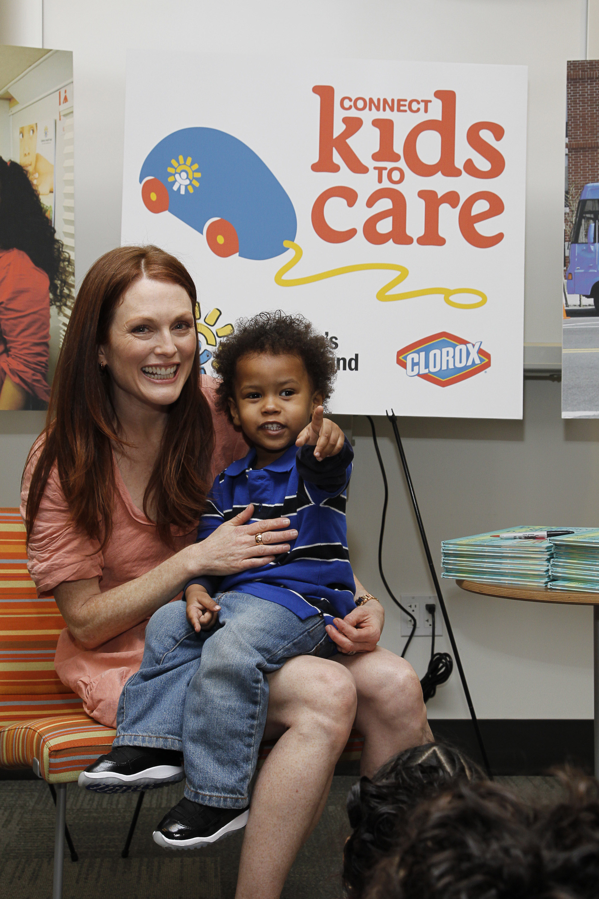 Julianne Moore sits with Jorge, age 2 1/2 reads from her book, Freckleface Strawberry and the Dodgeball Bully, to the Children's Health Fund's New York Program in New York on April 2010 to kick-off Connect Kids to Care program | Source: Getty Images