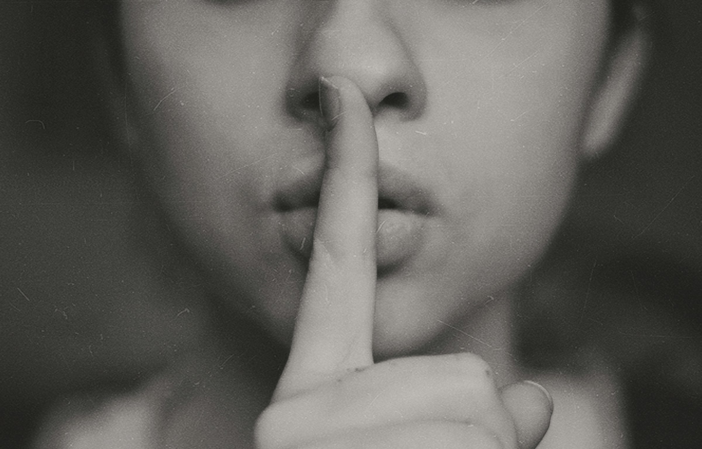 A grayscale photo of a woman doing a silent hand sign | Source: Unsplash