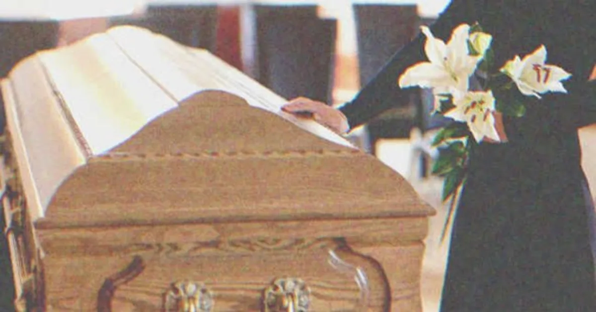 Femme tenant des fleurs et touchant un cercueil funéraire | Photo : Shutterstock