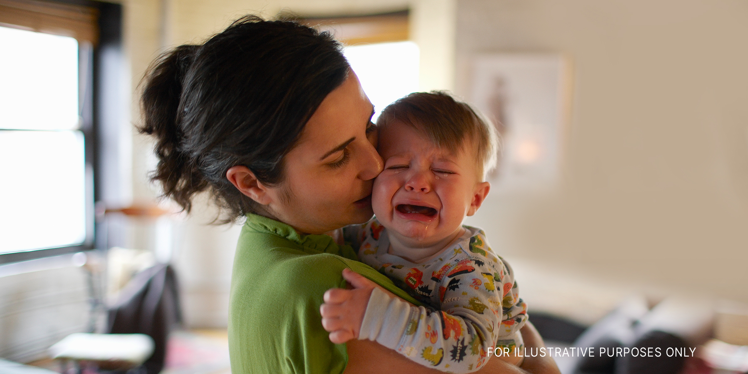 A mother holds and kisses her crying baby | Source: Getty Images