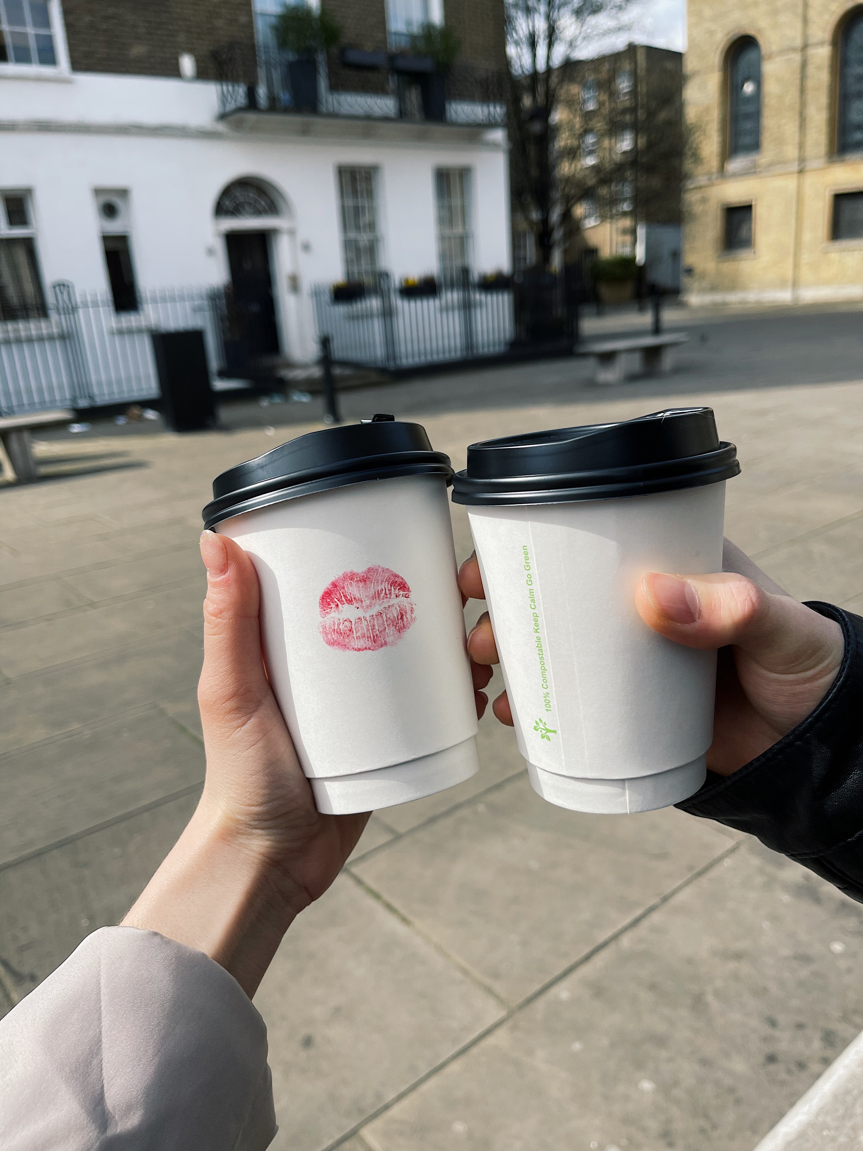 Two individuals holding coffee cups up, of which one of the cups has a lipstick kiss stain. | Source: Pexels