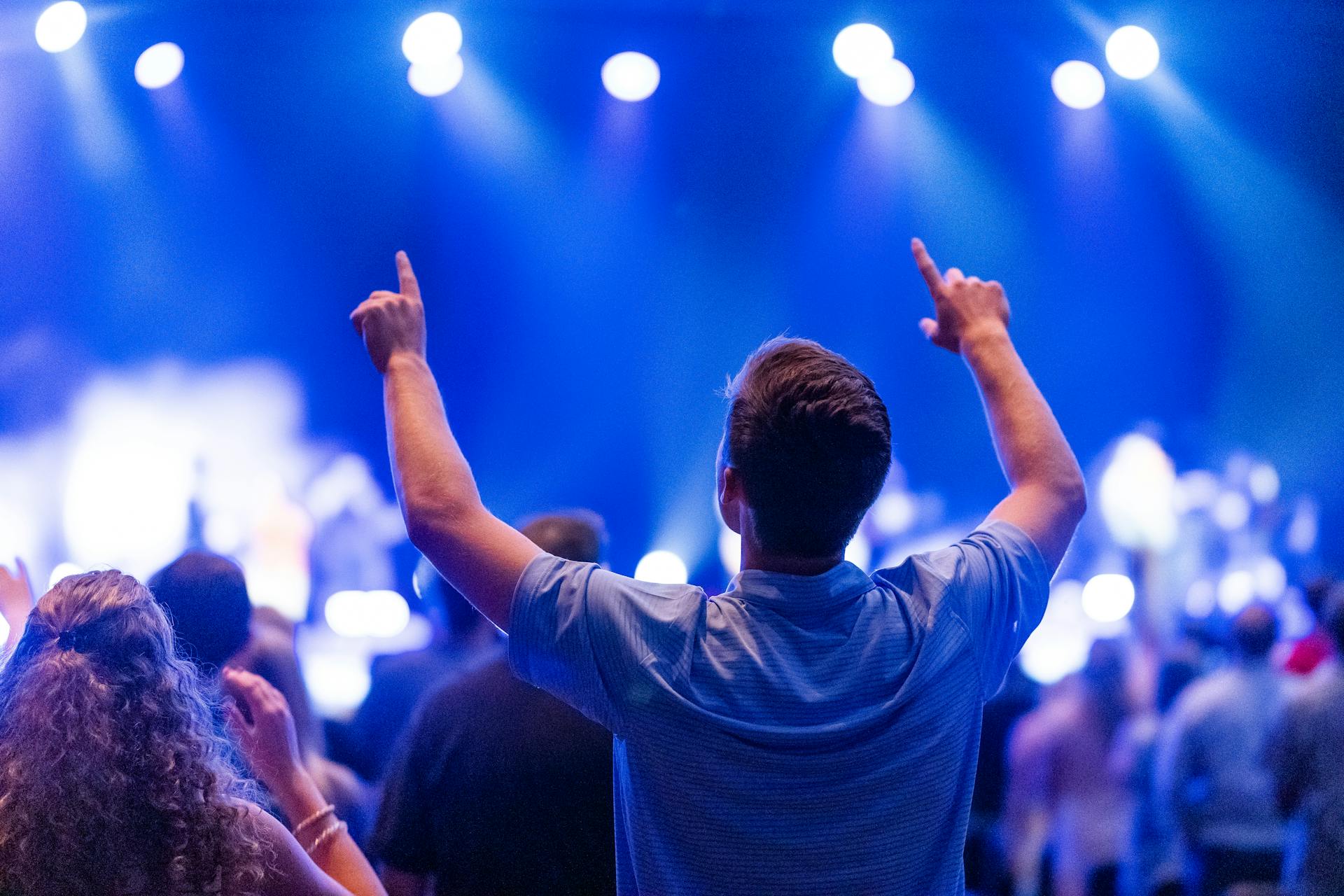 A man in a blue shirt raising his hands during a concert | Source: Pexels