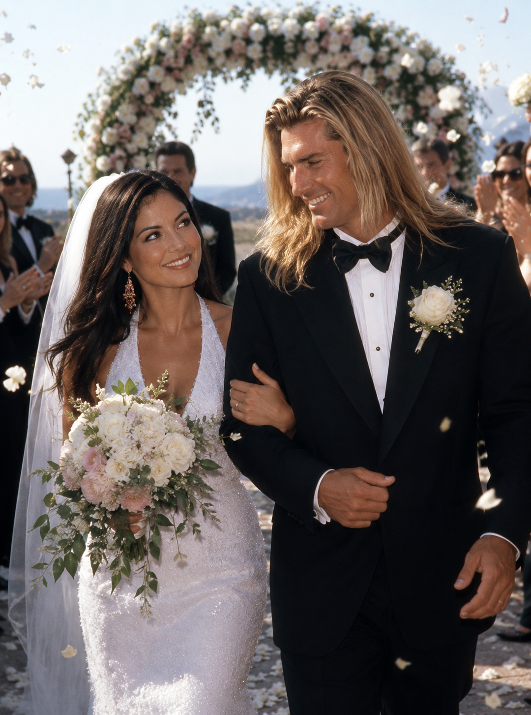 This AI creation portrays Fabio escorting Larissa Meek down the aisle as flower petals fall, featuring a beaded halter gown, lush bridal bouquet, and a grand floral arch. | Source: ChatGPT