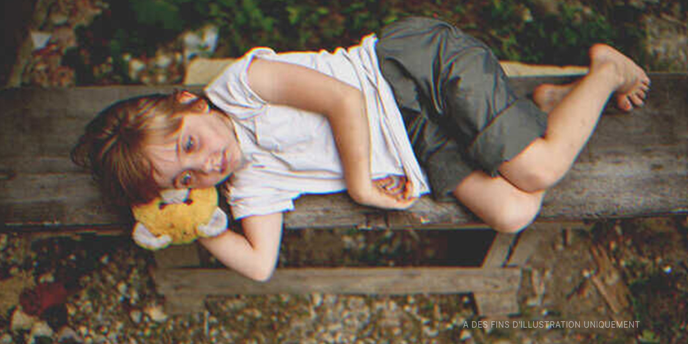 une petite fille couchée sur un banc public І Source : Shutterstock