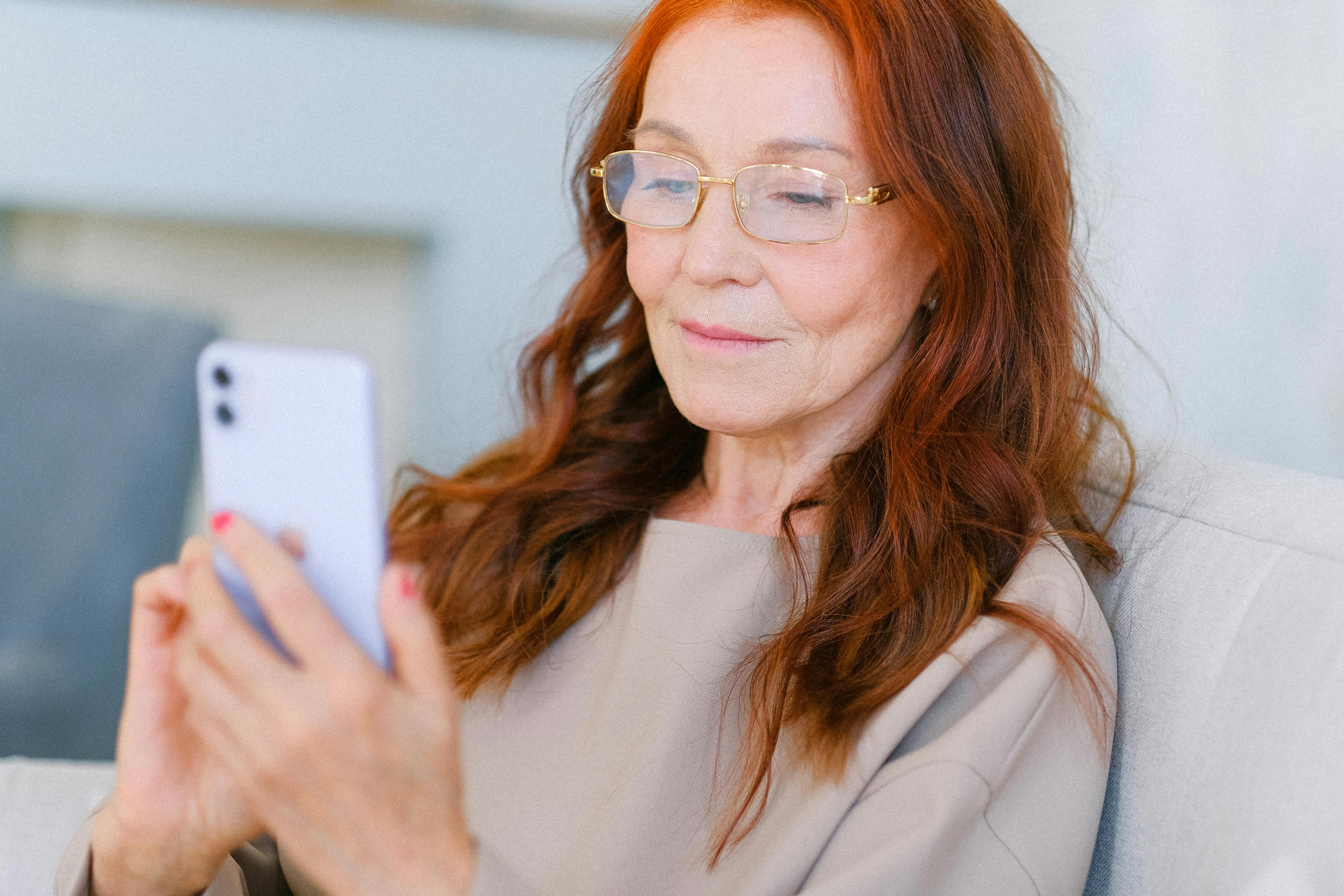 Elderly woman smiles at her phone | Source: Pexels