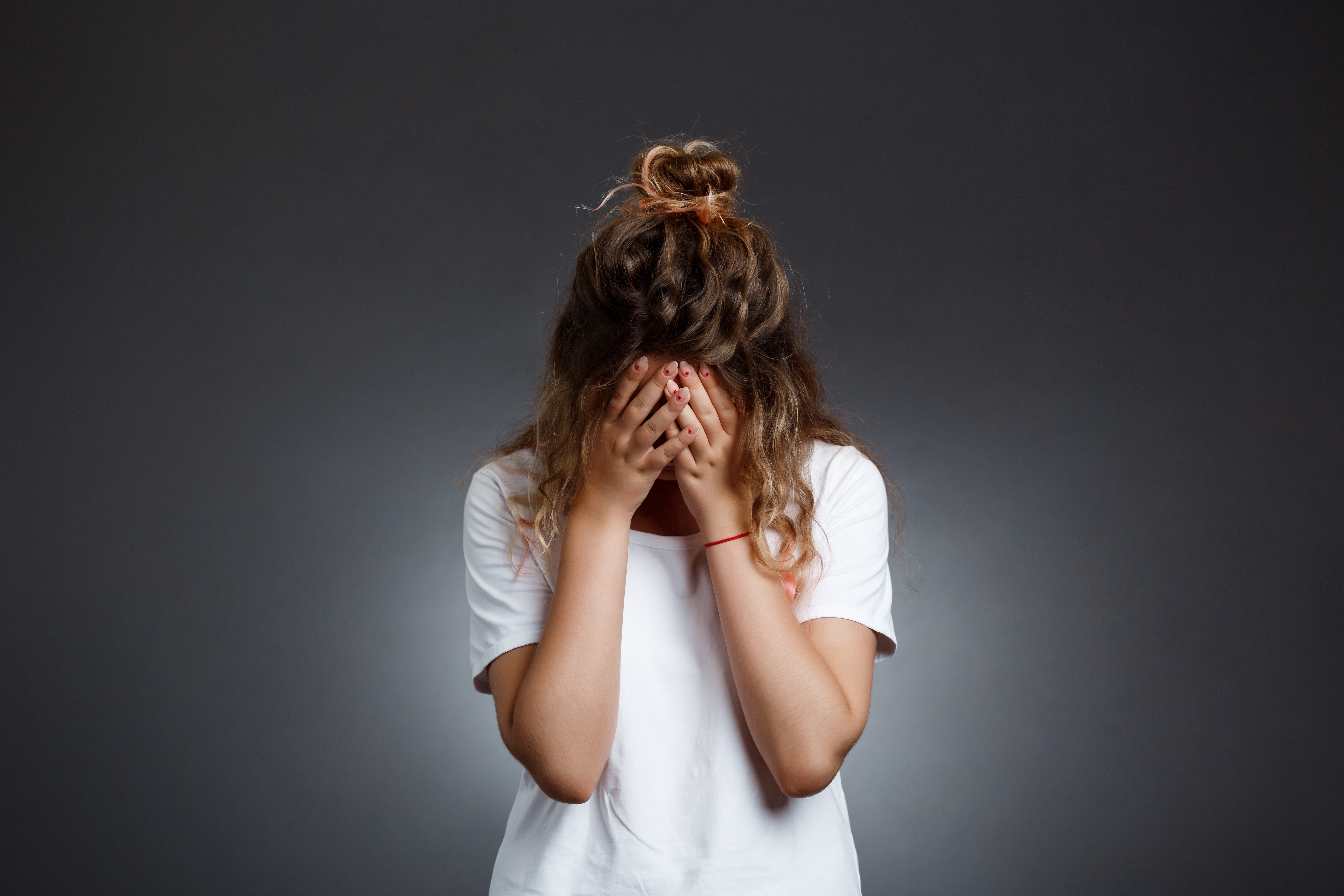 Upset young woman with her head in her hands | Source: Shutterstock