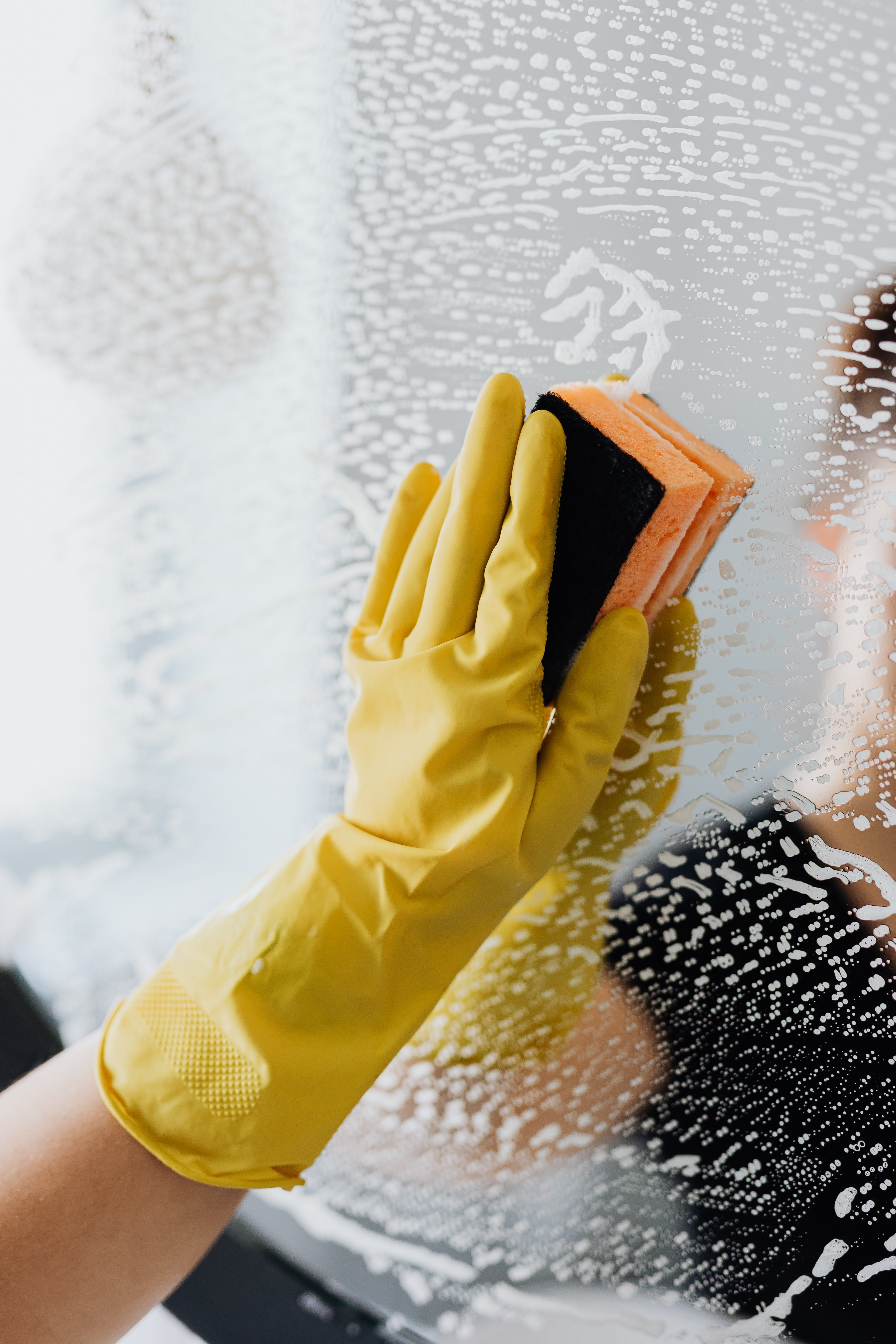 A person cleaning the mirror with a sponge | Photo: Pexels 