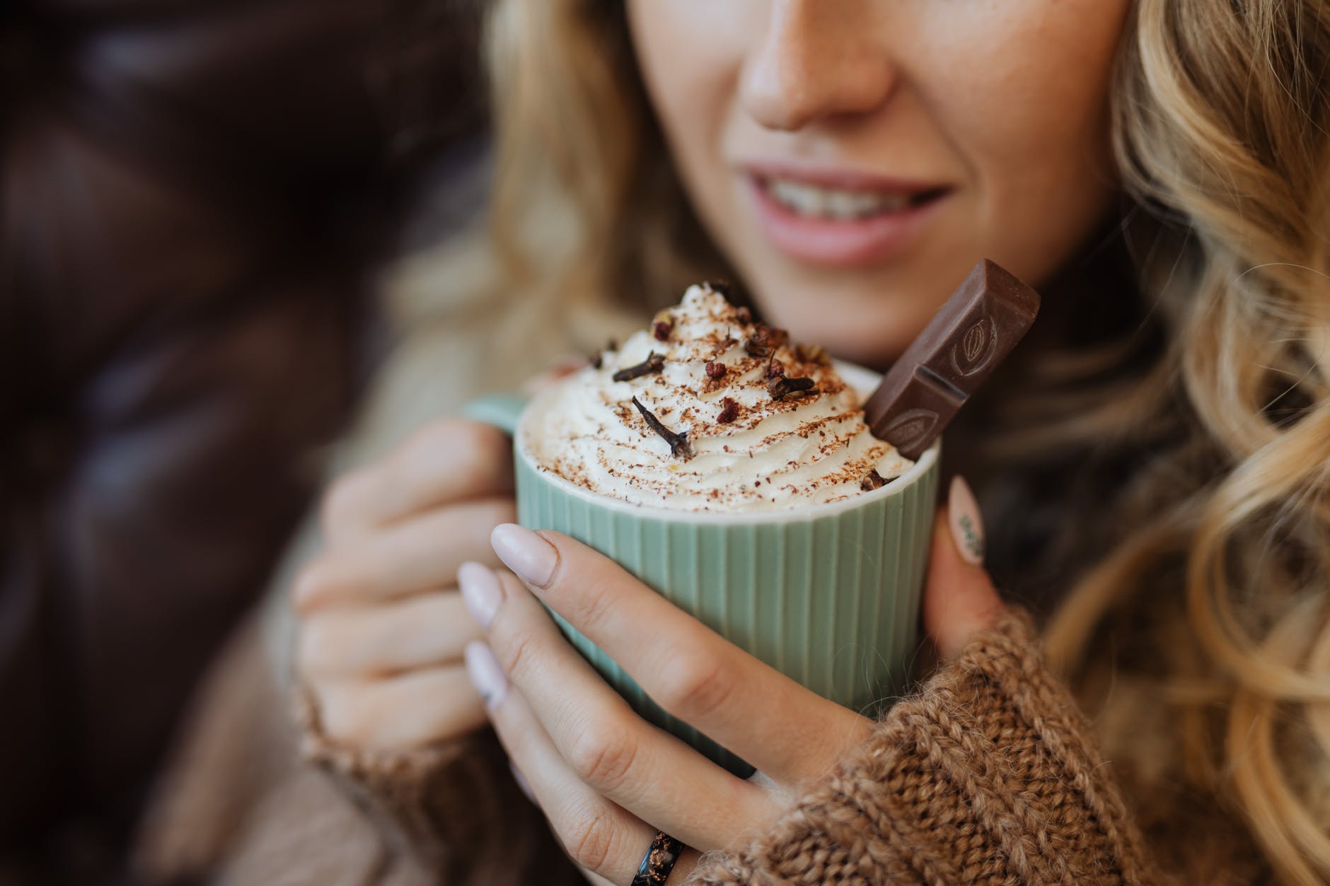 Una mujer tomando una taza de chocolate con crema batida. | Foto: Pexels