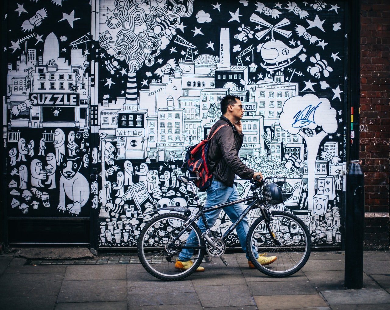 Photo of young man pushing his bicycle in the city. | Source: Pexels/Clem Onojeghuo