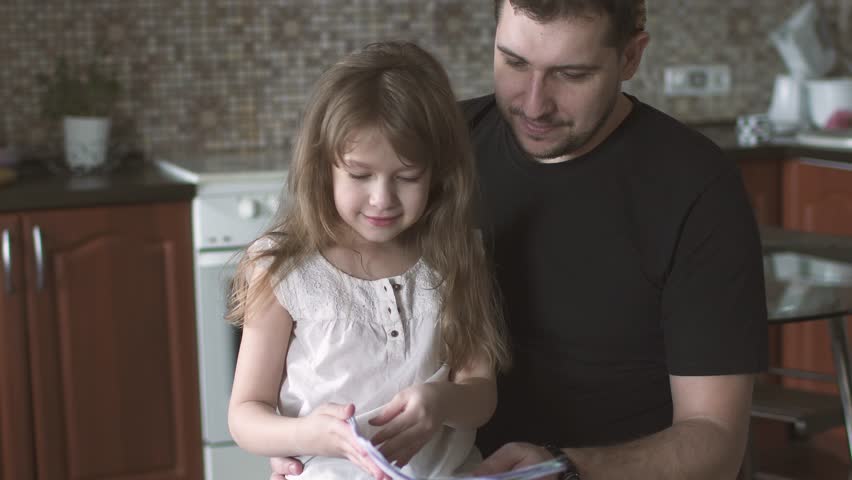 Photo of a young girl sitting on her father's laps, smiling | Photo: Shutterstock.com