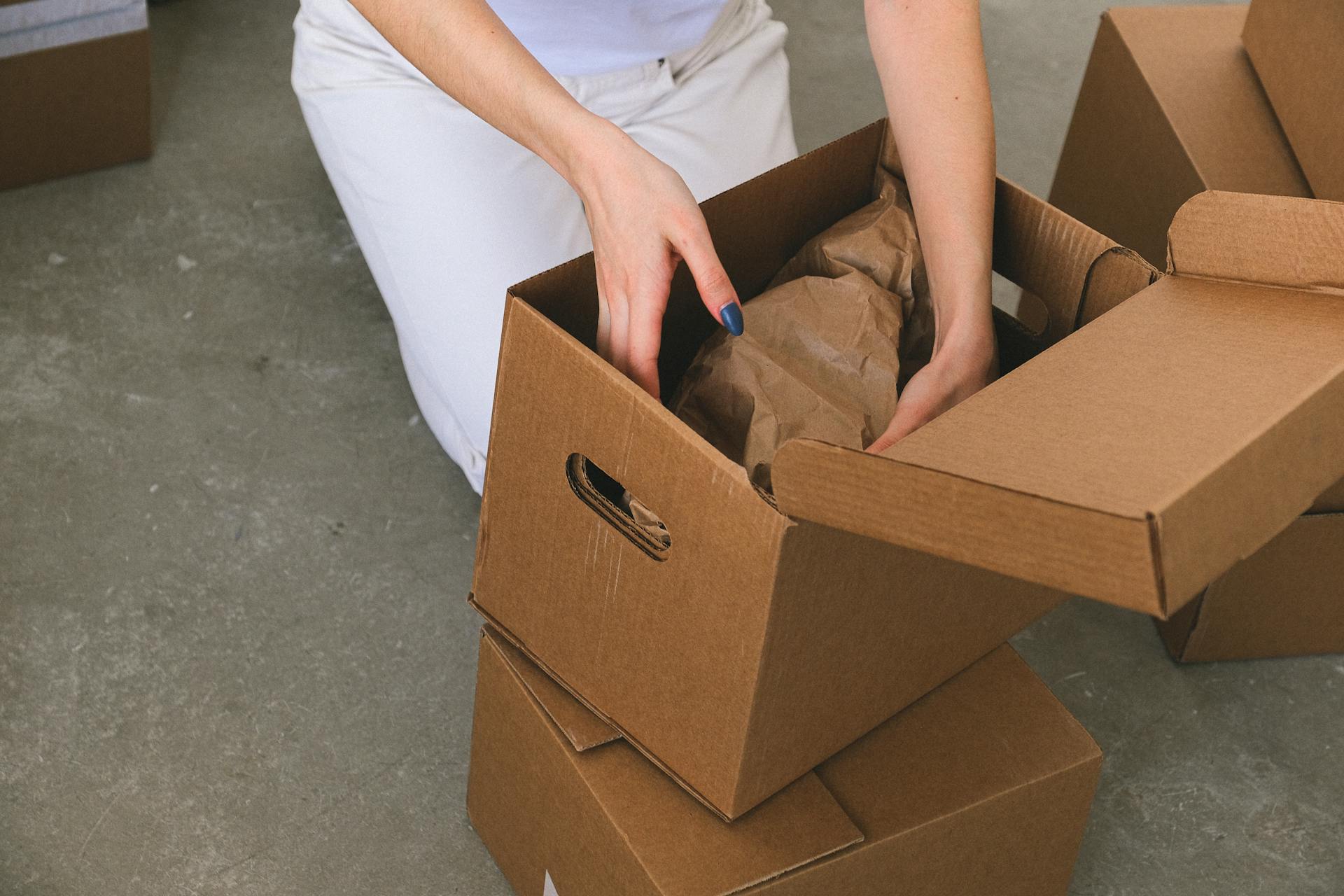 A woman arranging cardboard boxes | Source: Pexels