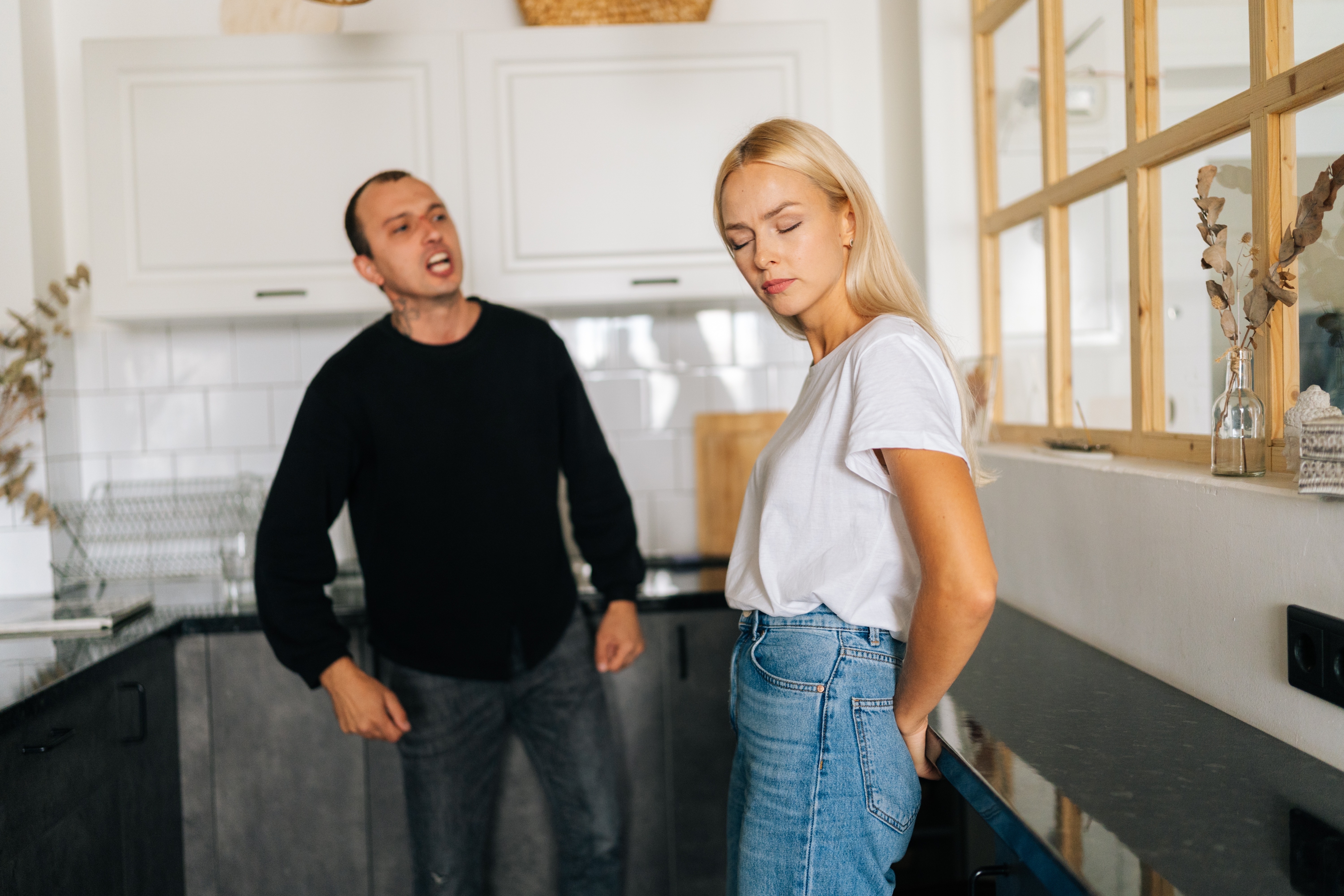 A woman stands in the kitchen with her eyes closed as her man shouts at her | Source: Shutterstock