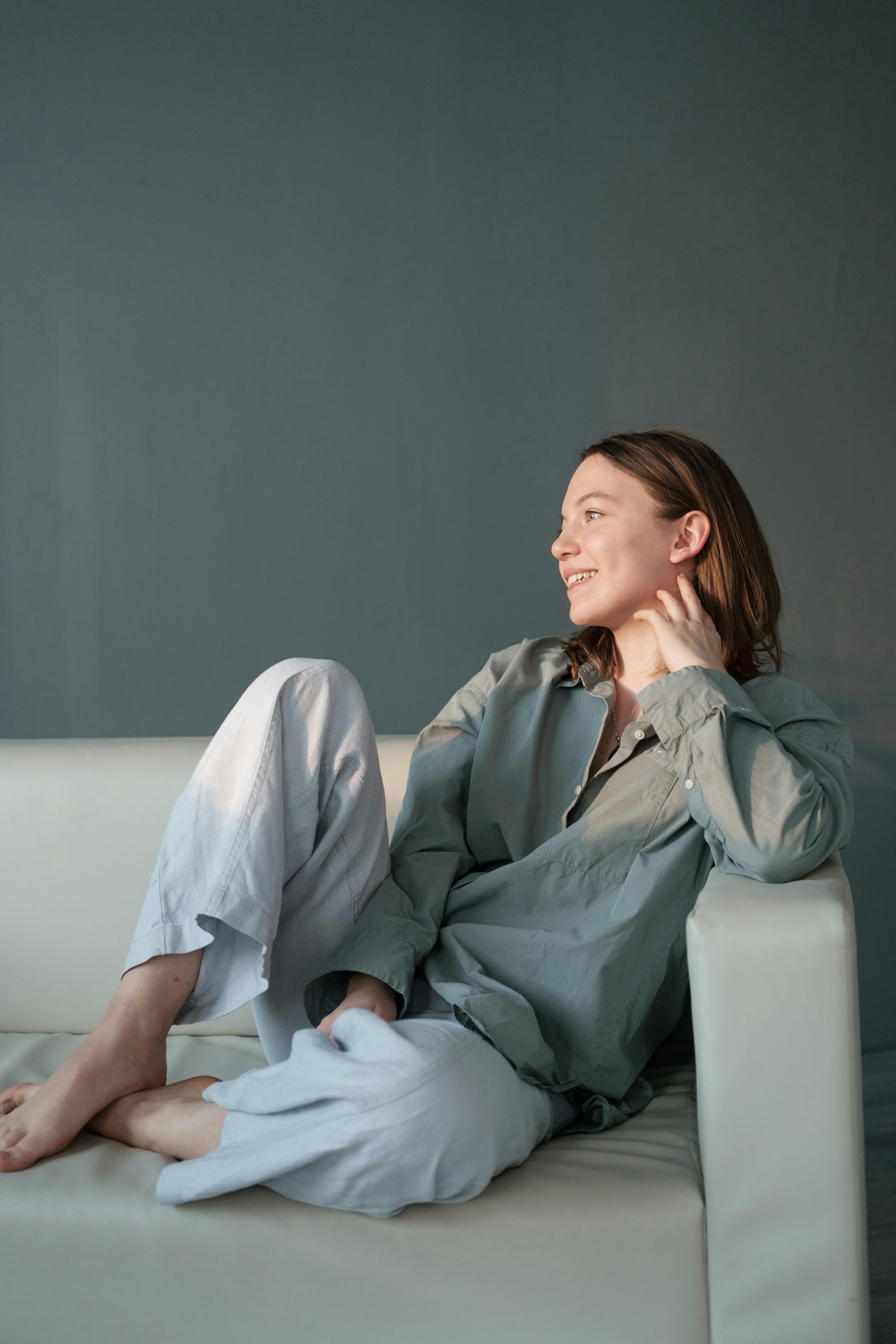 Smiling woman sitting on couch with legs crossed | Source: Pexels