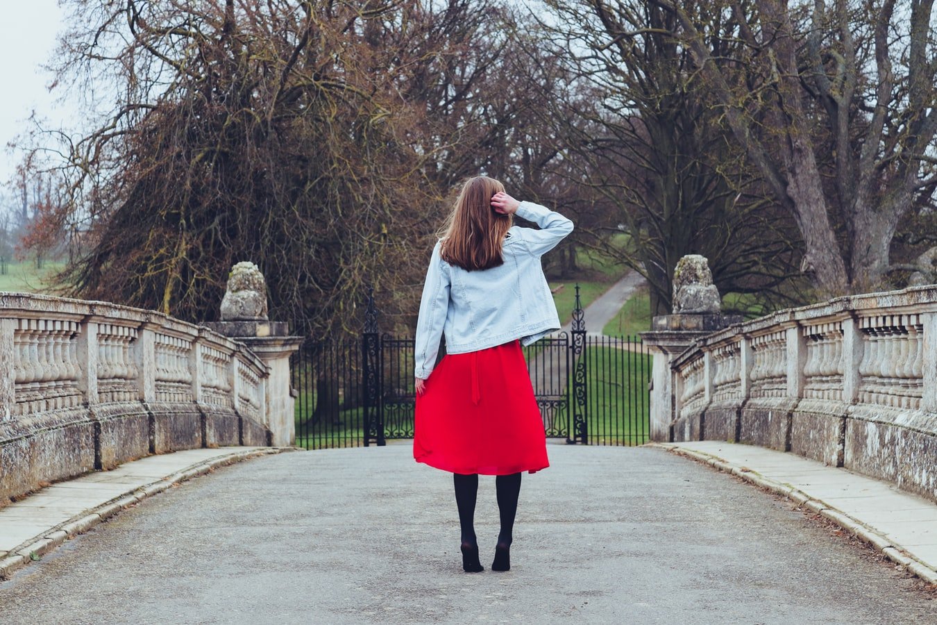 Une femme vêtue d'une jupe rouge et d'un manteau en jean. l Source : Unsplash