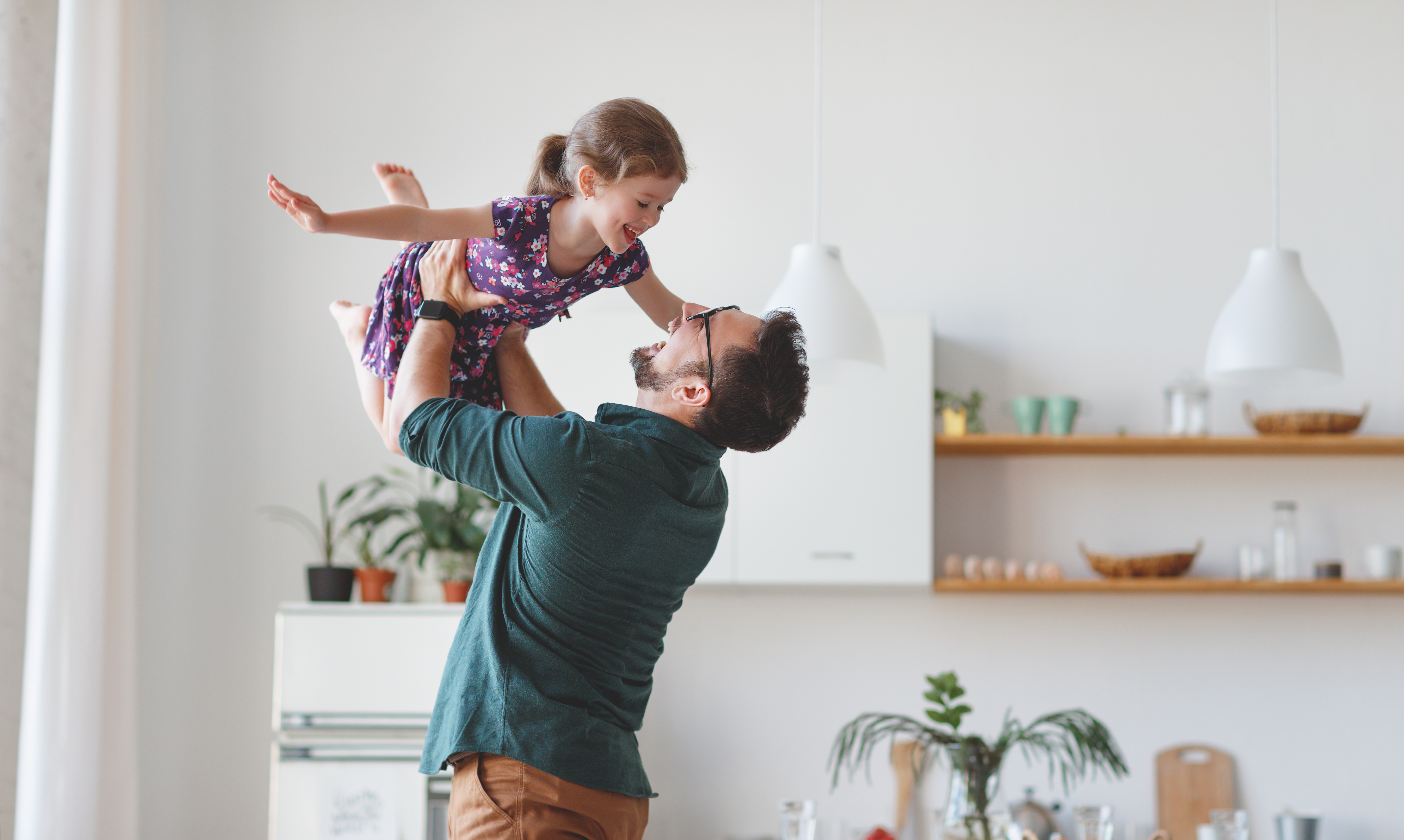 A man holding his daughter above his head as he smiles up at her | Source: Shutterstock