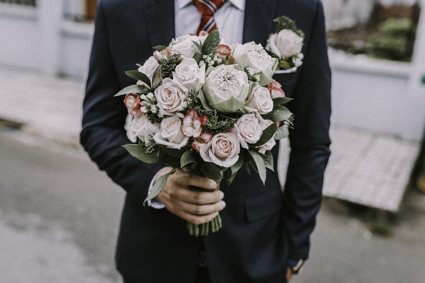 Hombre vestido con elegancia lleva un ramo de flores. | Foto: Unsplash