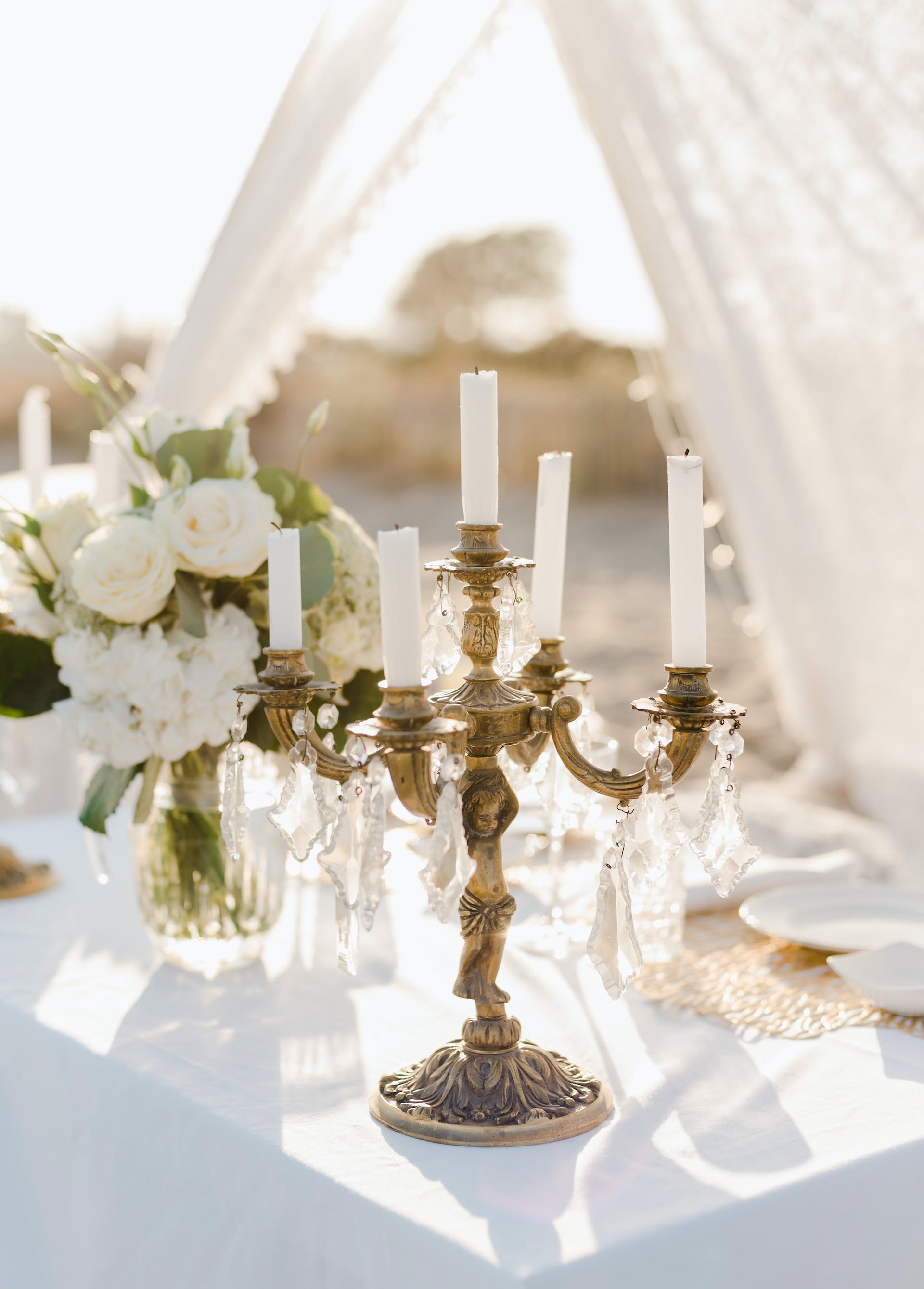 Elegant candle holders and a white bouquet in a vase | Source: Pexels