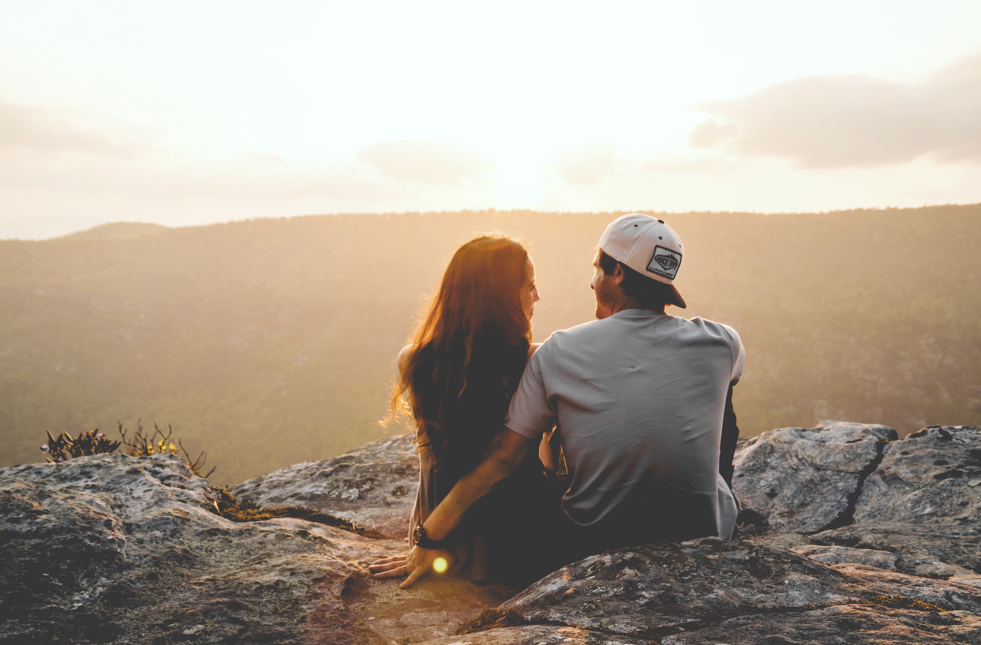 A couple sitting on a cliff together. | Source: Unsplash