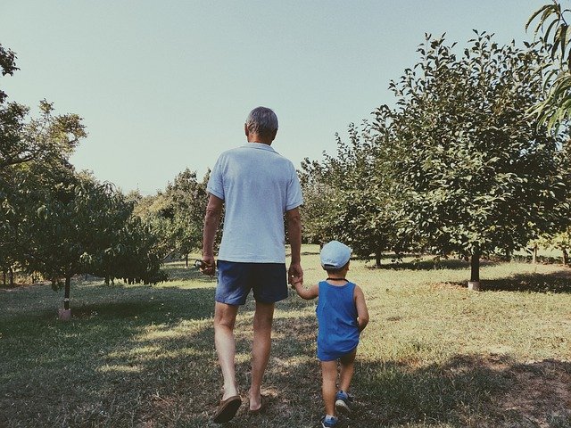 Old man walks through orchard with young boy | Photo: Pixabay
