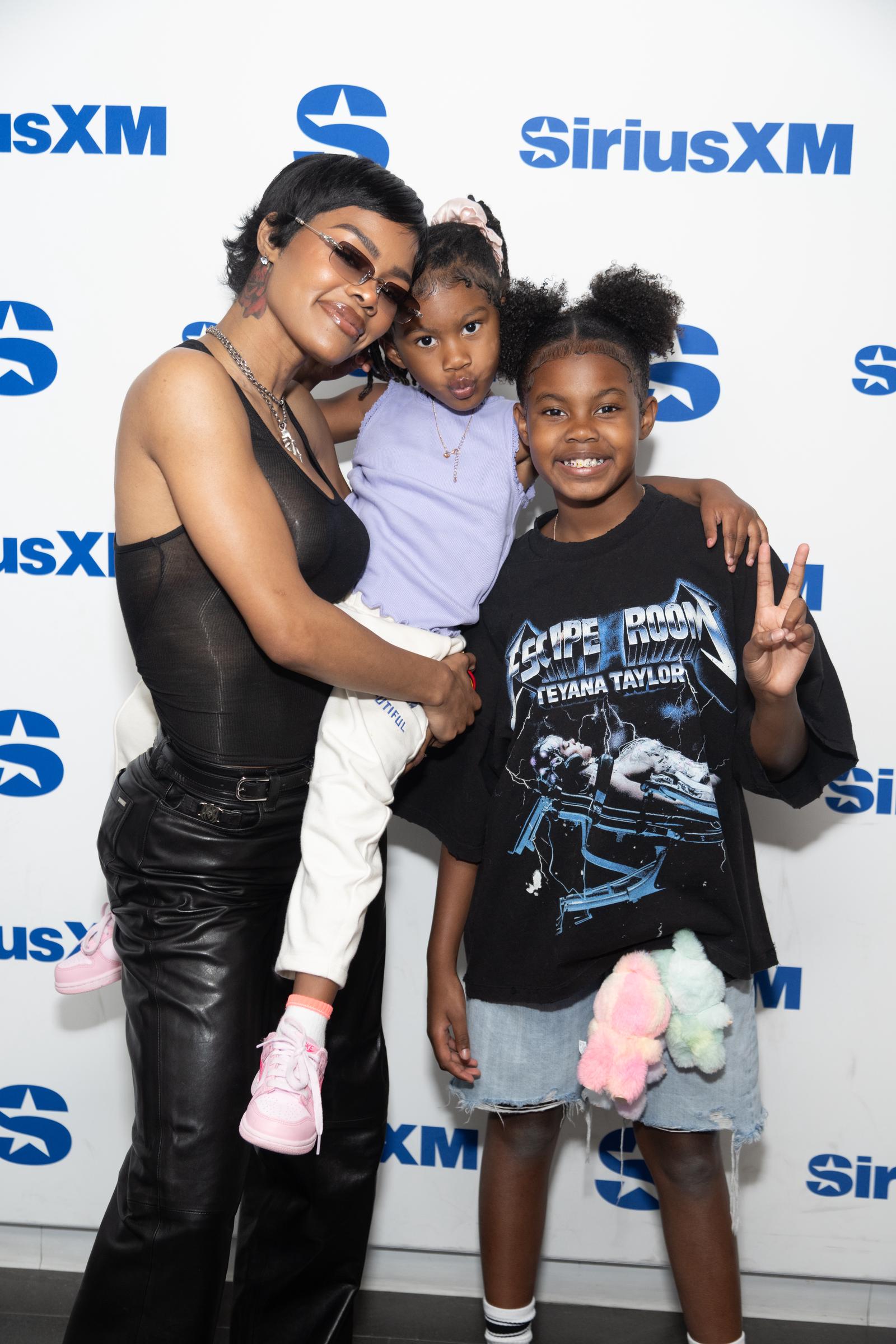 Teyana Taylor visits SiriusXM Studios in New York City with Rue Rose Shumpert and Iman Tayla "Junie" Shumpert Jr. Rue is held close while Junie smiles and flashes a peace sign.