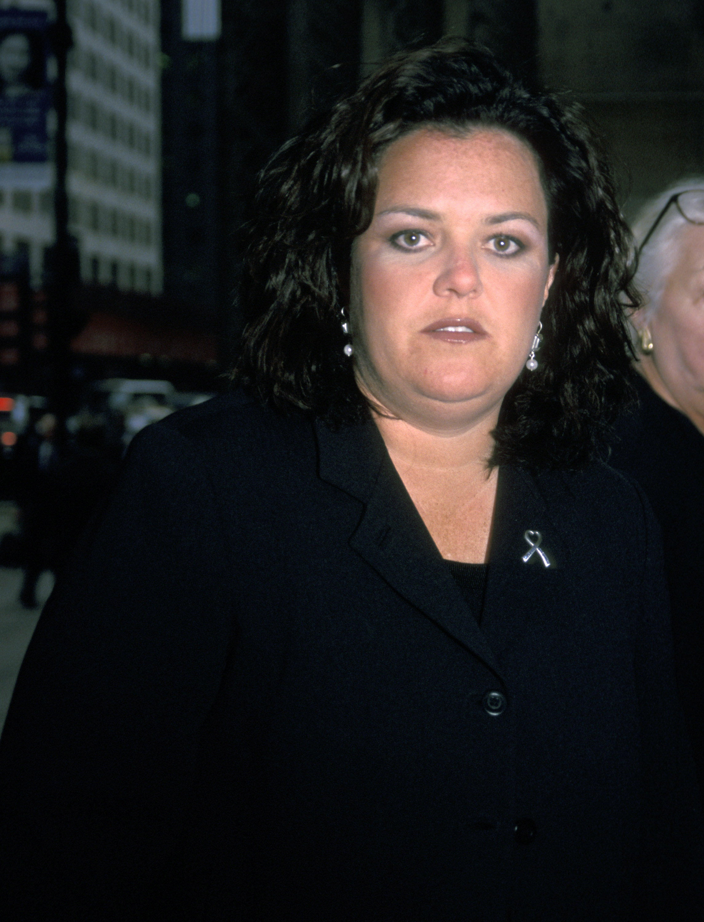 Rosie O'Donnell arrives at Handgun Control Inc.'s event at Cipriani's in New York City, photographed in a candid street-style moment with glowing lights and traffic behind her.