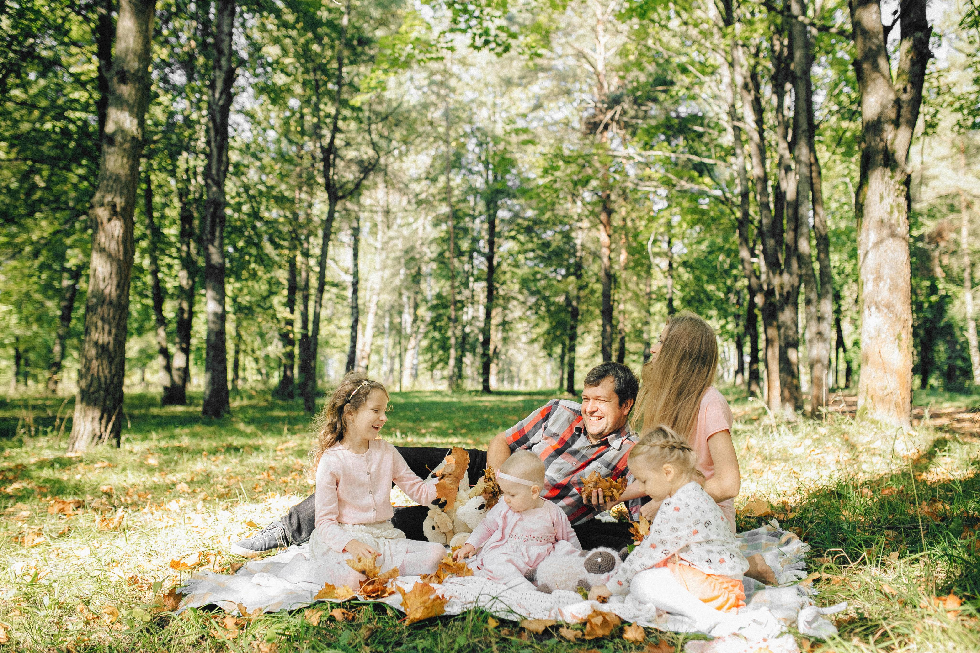 Parents and their three young children enjoying a picnic | Source: Pexels