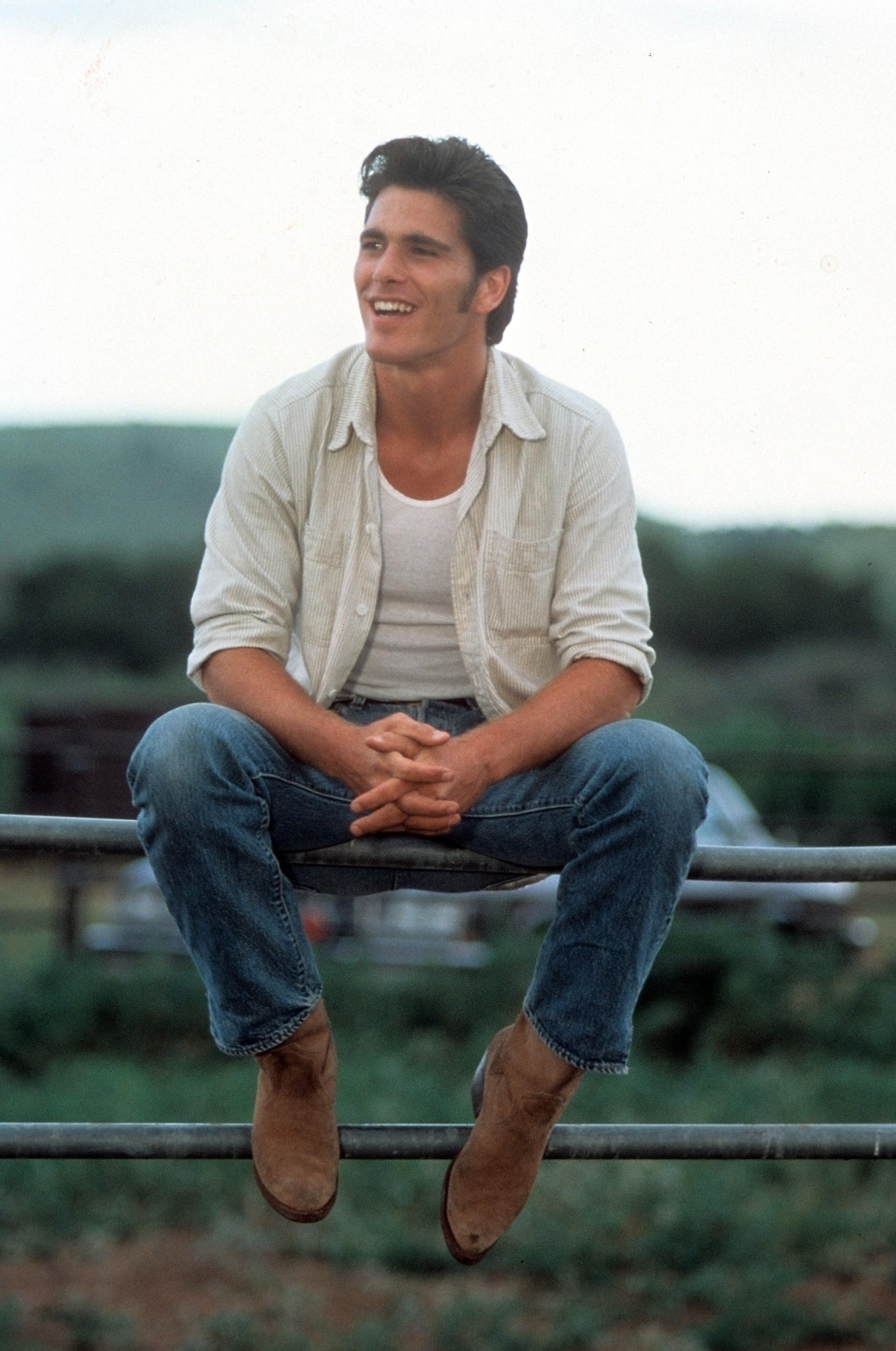 Michael Schoeffling is pictured sitting on a fence in a scene from the movie "Sylvester," circa 1985 | Source: Getty Images