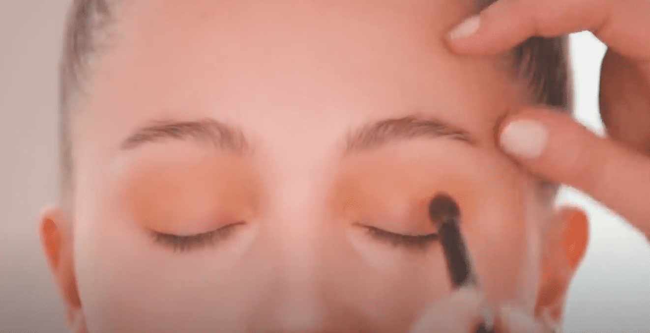 Makeup artist Caitilin Wyman applies eyeshadow on a model's eyelids. | Source: YouTube/ScottBarnes