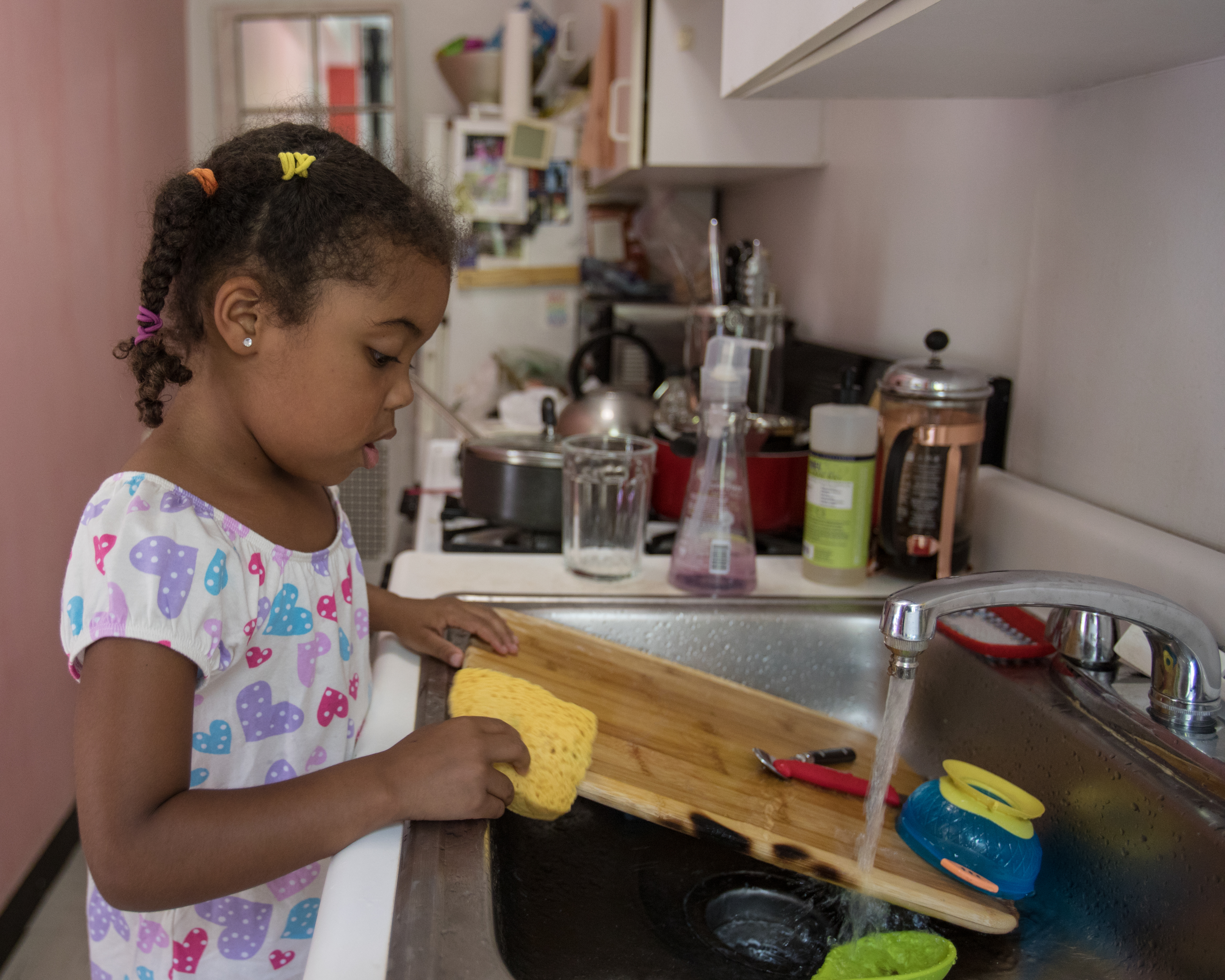 A young girl washes dishes in a kitchen | Source: Getty Images
