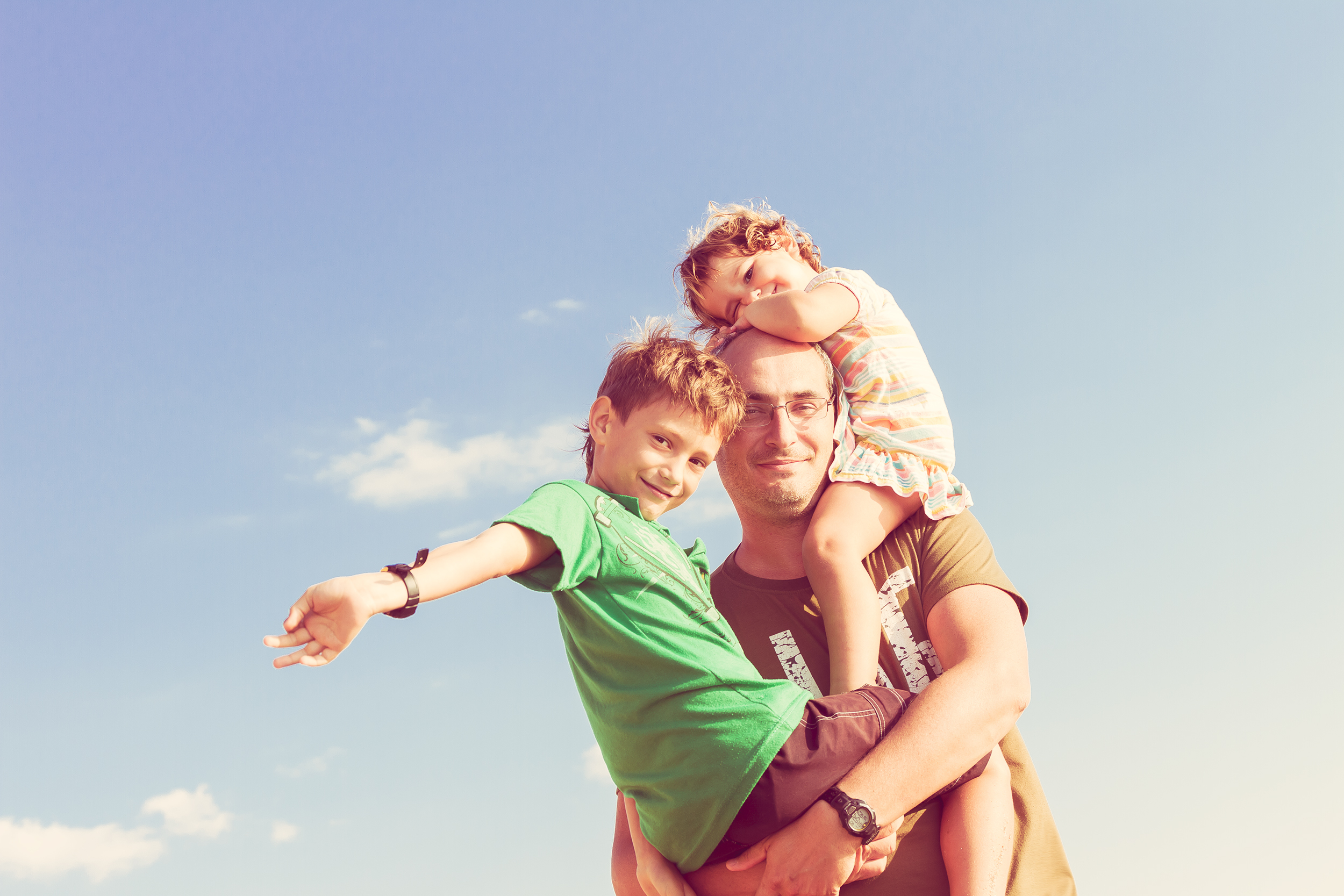 A father holding his son in his arms and his daughter on his shoulders | Source: Shutterstock