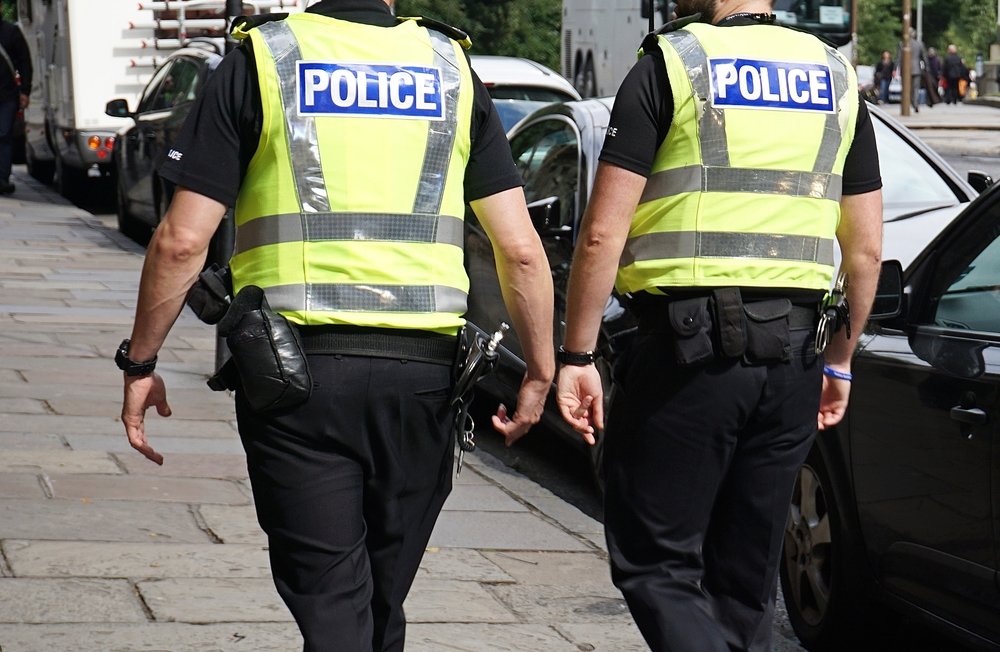 Two police officers fully clothed in their work gear and walking together while on duty | Photo: Shutterstock/Tana888