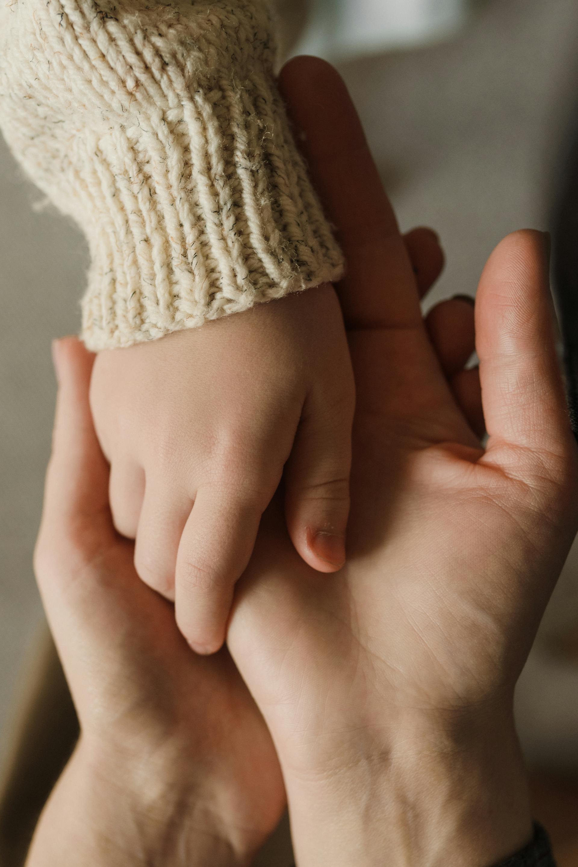 A little girl holding on to her father's hands | Source: Pexels