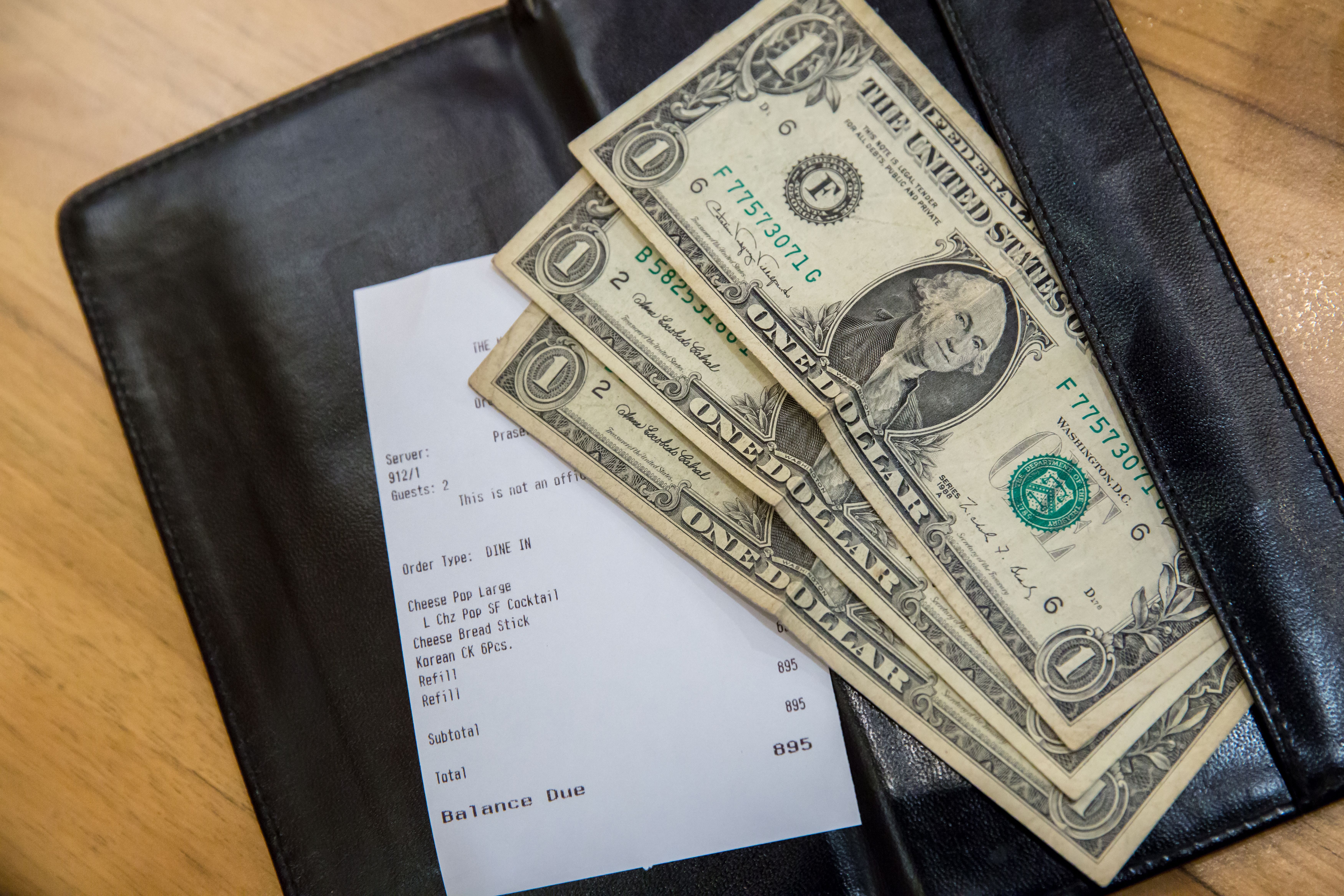 A restaurant bill and a few dollars. | Source: Shutterstock