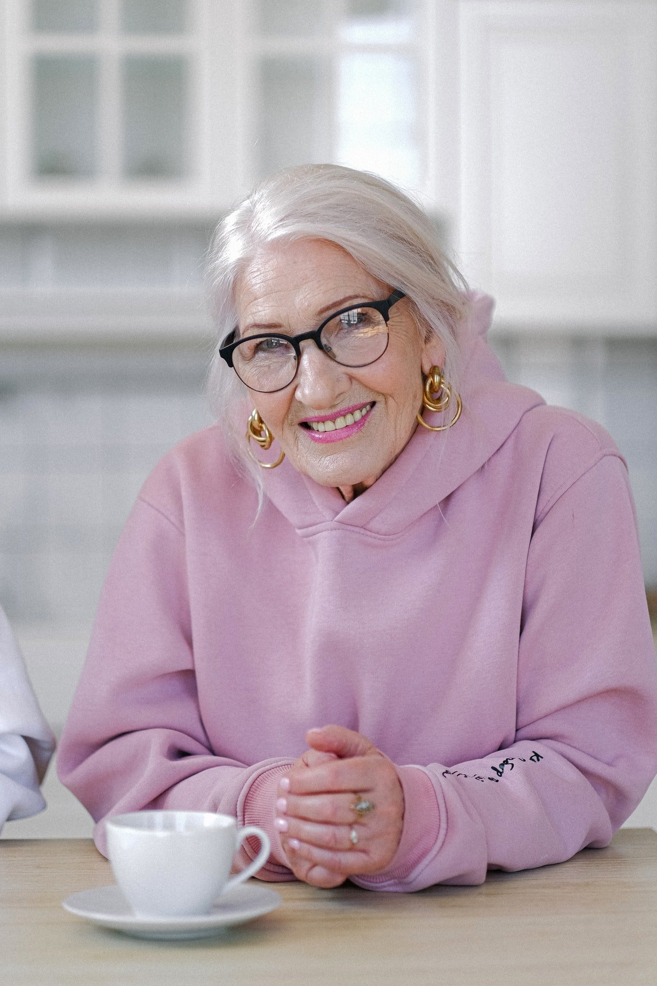 Una mujer mayor sonriendo sentada frente a una mesa. | Foto: Pexels